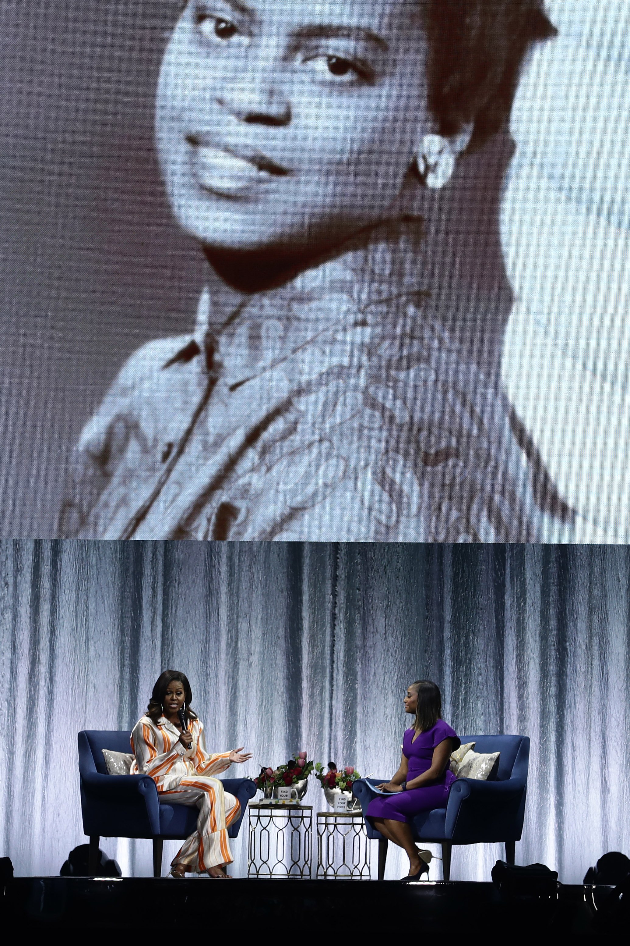 Michelle Obama speaking in front a picture of her younger self | Photo: Getty Images