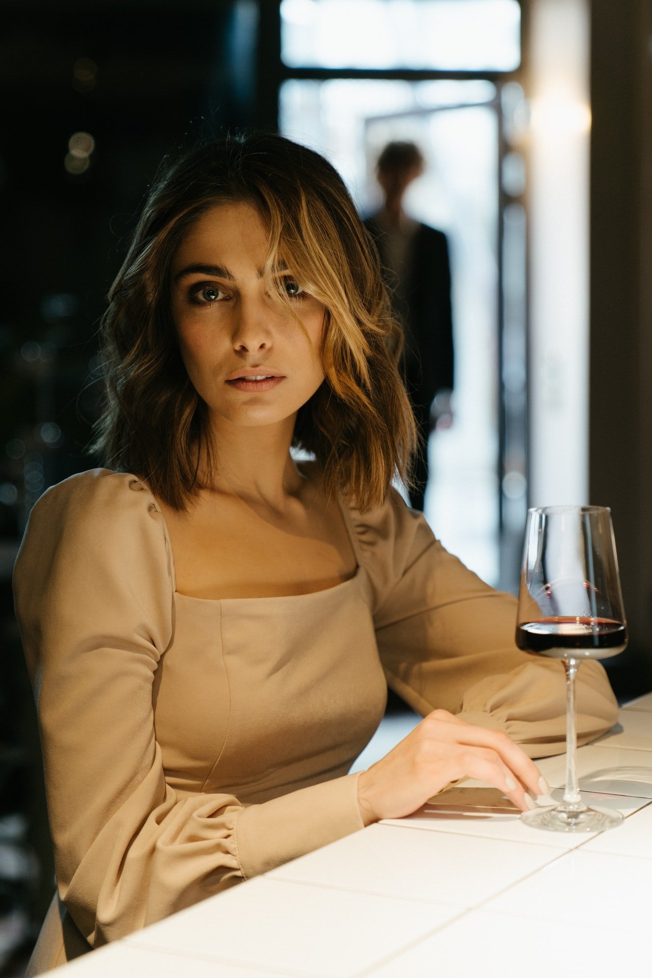 Photo of a woman in a restaurant holding a wine glass | Photo: Pexels