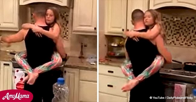 Dad dances adorably with his daughter while cooking in the kitchen