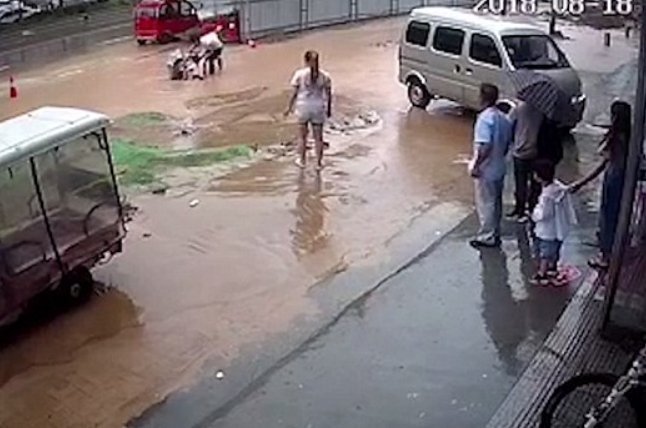 Personas ayudando a sacar a las niñas del agujero lleno de agua en la calle. | Imagen: Youtube/MobbieVlogs 