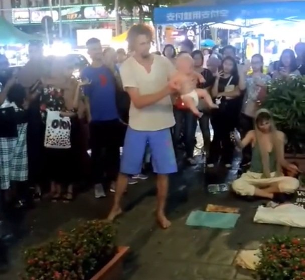 El padre balancea a su hija durante un espectáculo callejero en Kuala Lumpur. / Foto: Facebook / Zayl Chia Abdulla