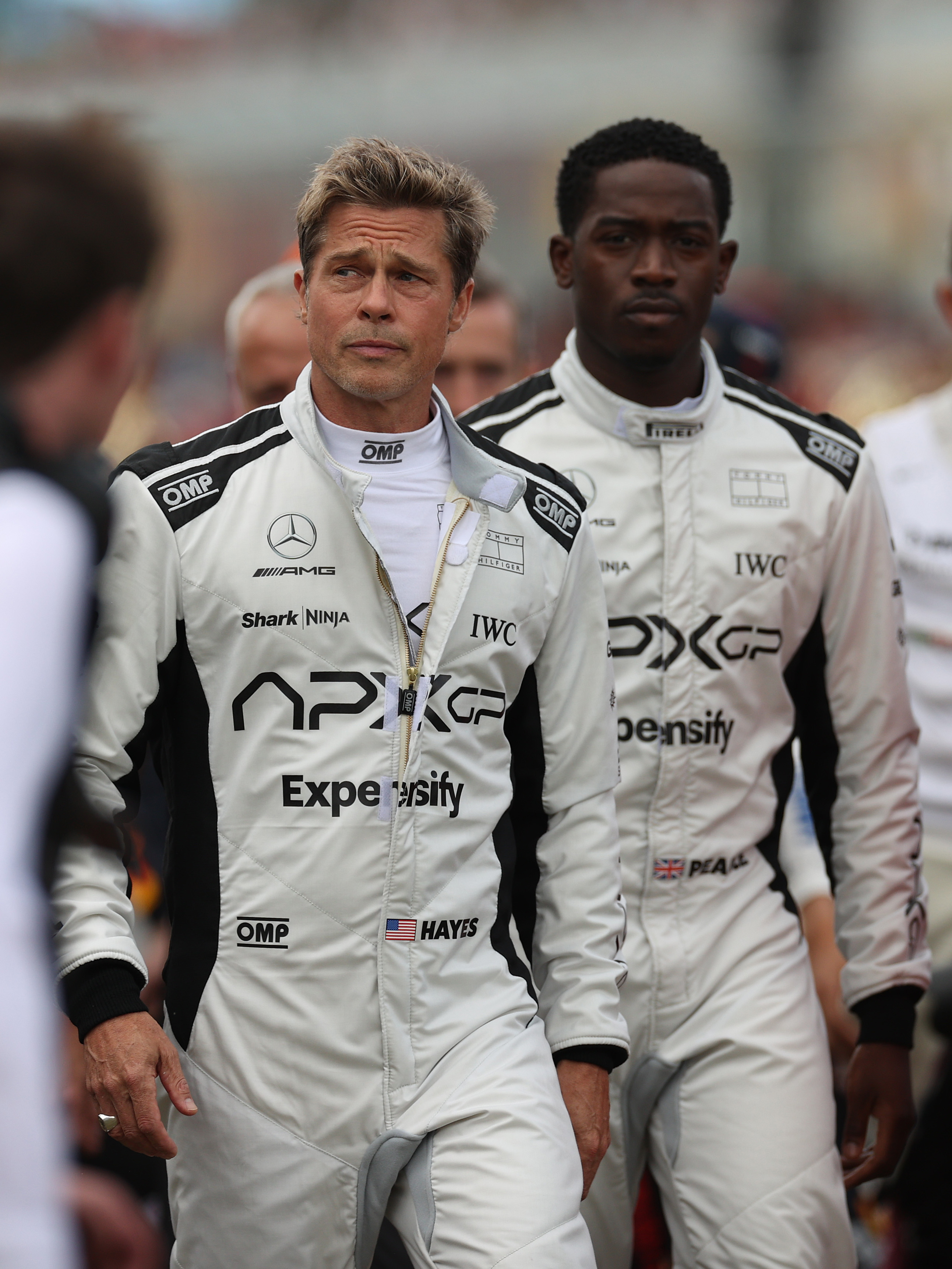 Brad Pitt and Damson Idris walk on the grid in front of Carlos Sainz of Spain driving the Ferrari SF-23 on track during the F1 Grand Prix of Great Britain in Northampton, England, on July 9, 2023 | Source: Getty Images