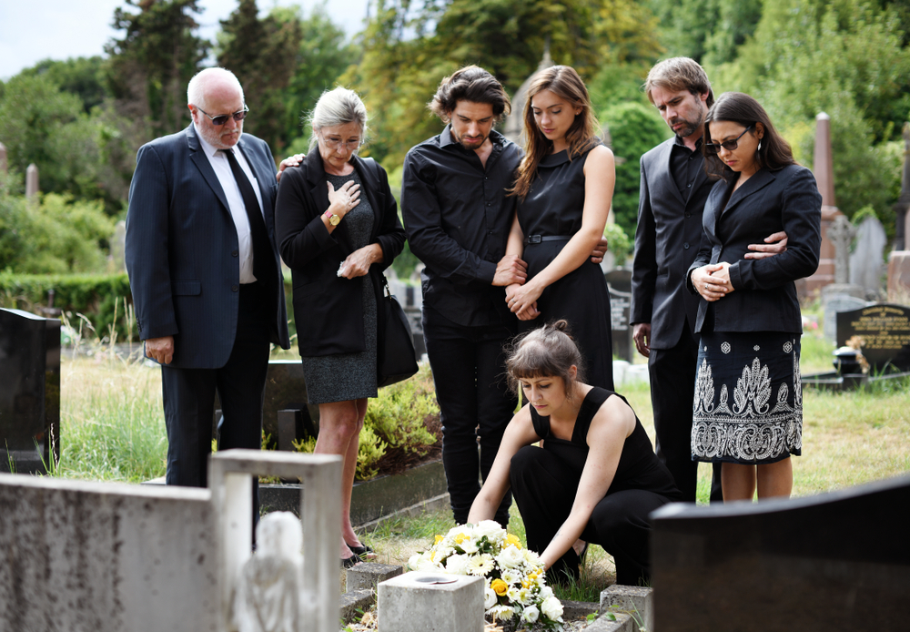 Family laying flowers on the grave.| Source: Shutterstock