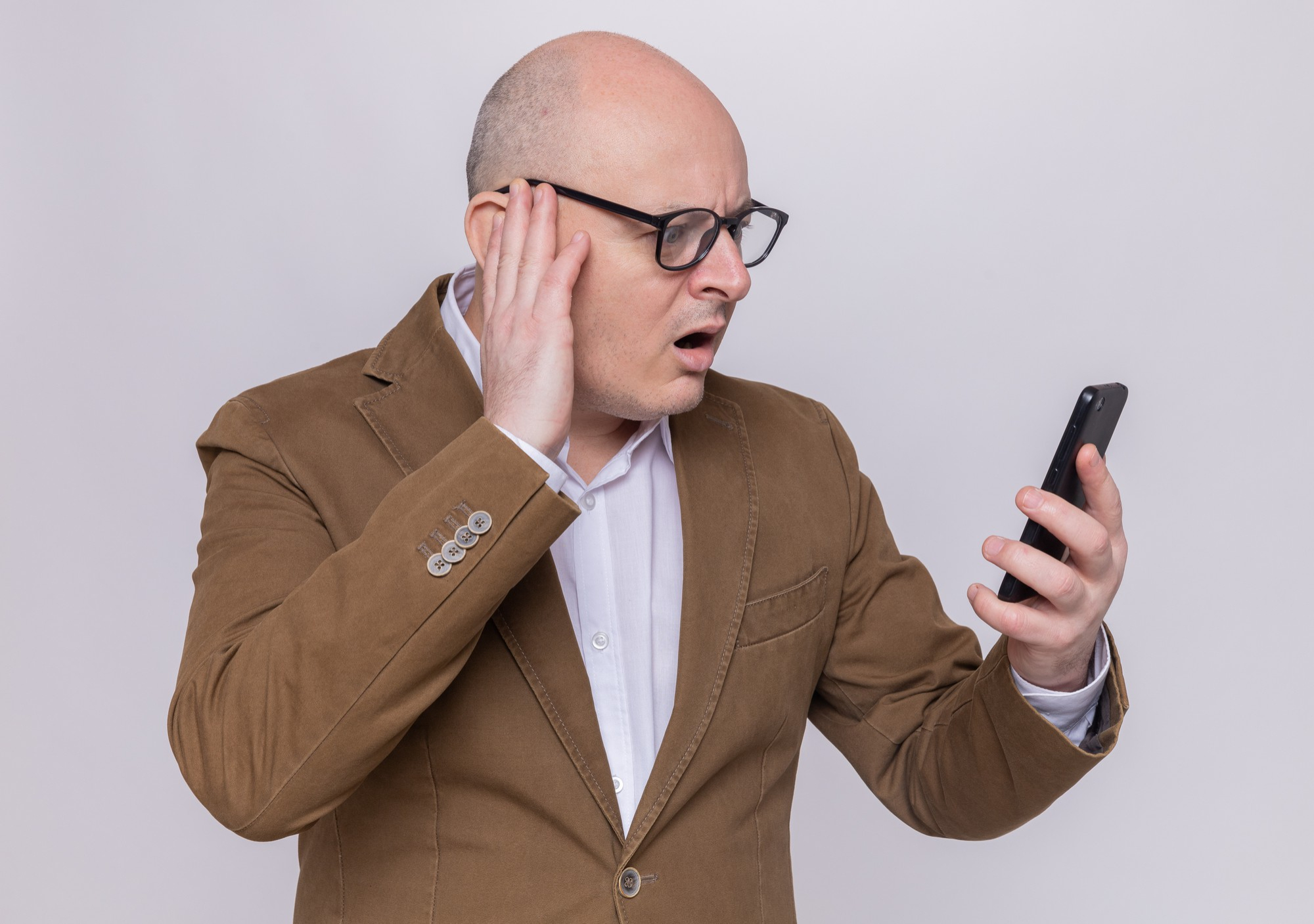 An upset and shocked man listening to a recording on his phone | Source: Pexels