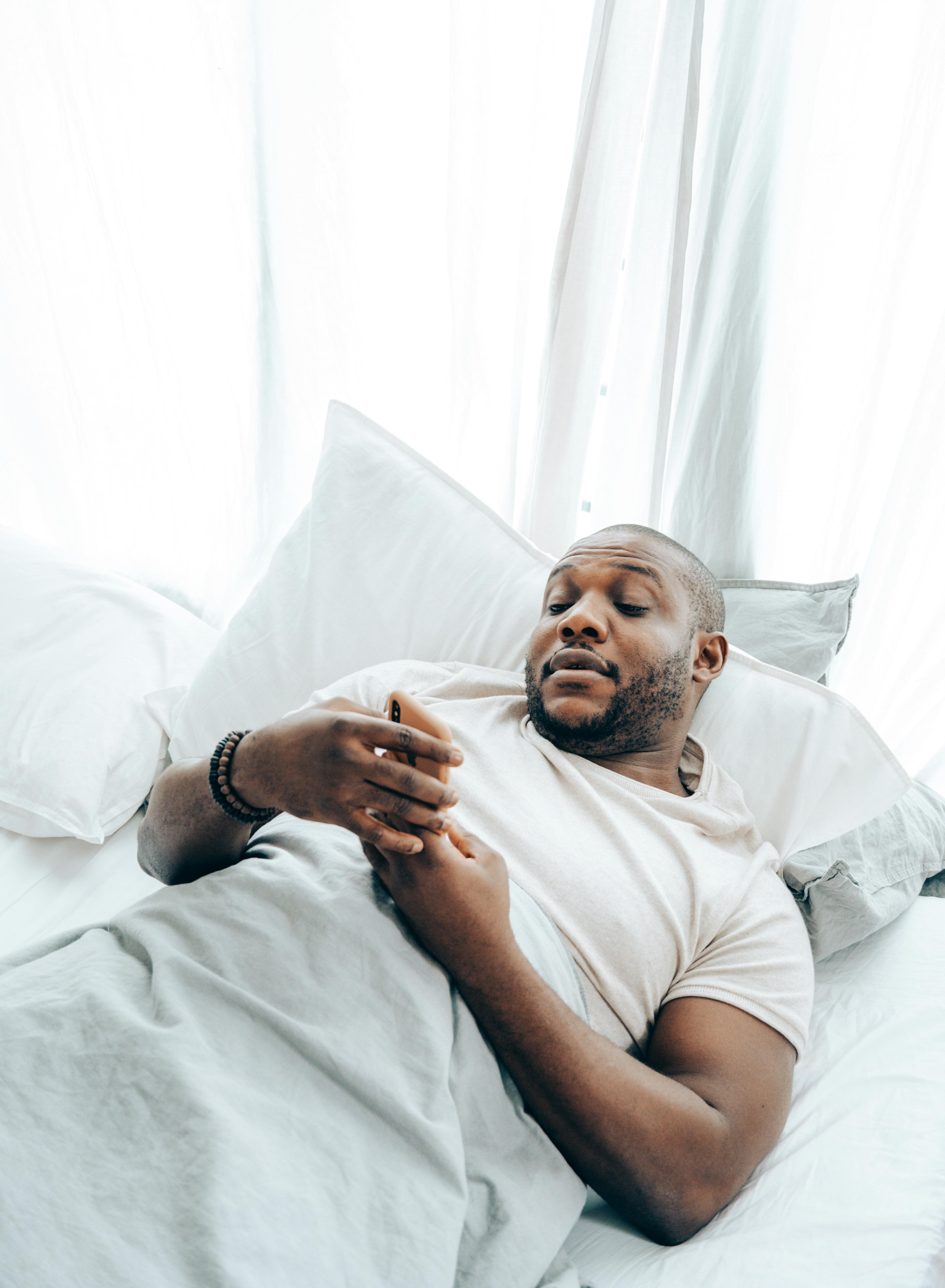 Black man talks on his phone in his bed | Source: Pexels