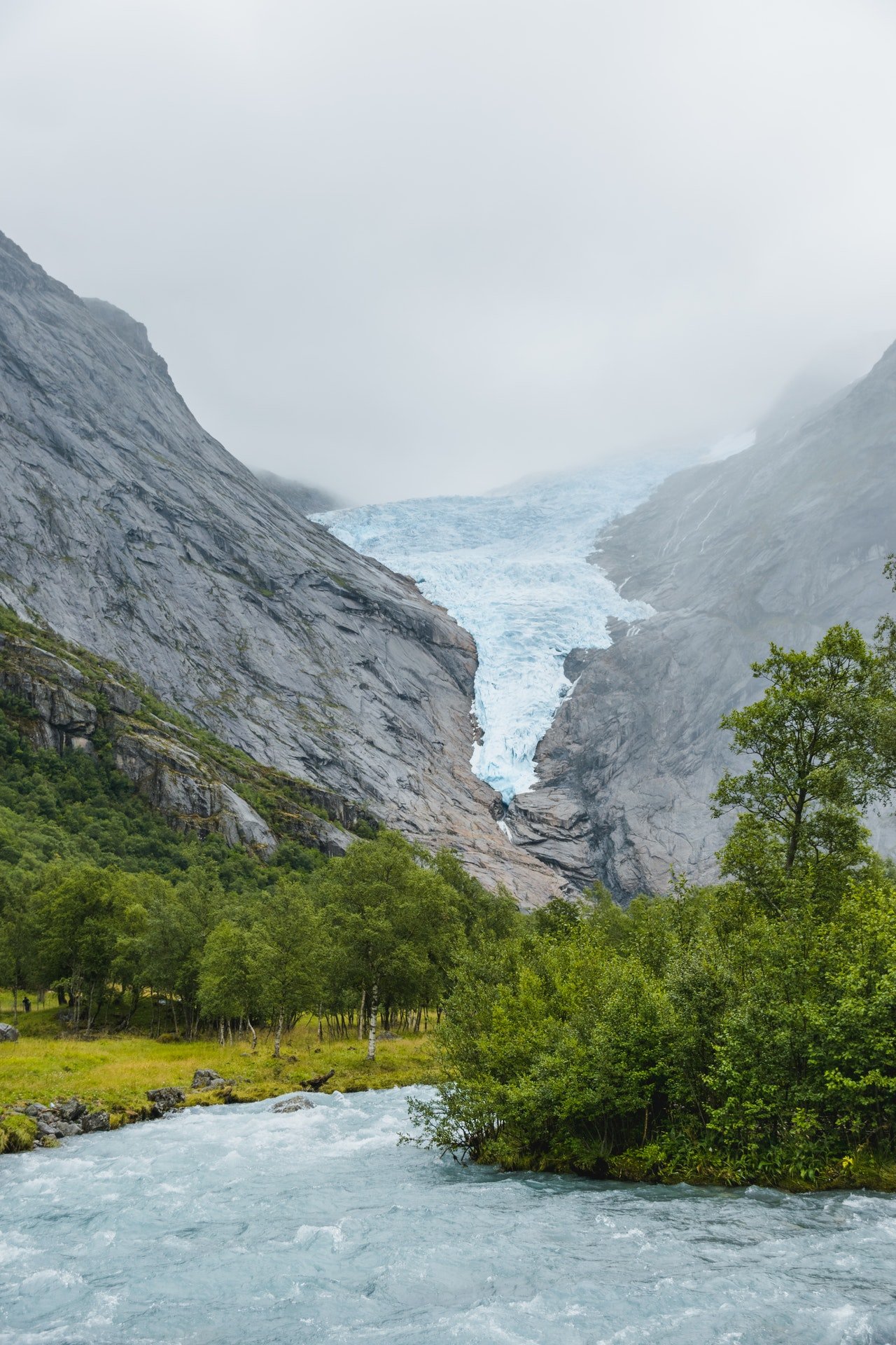 Photo of a river flowing by a mountain | Photo: Pexels