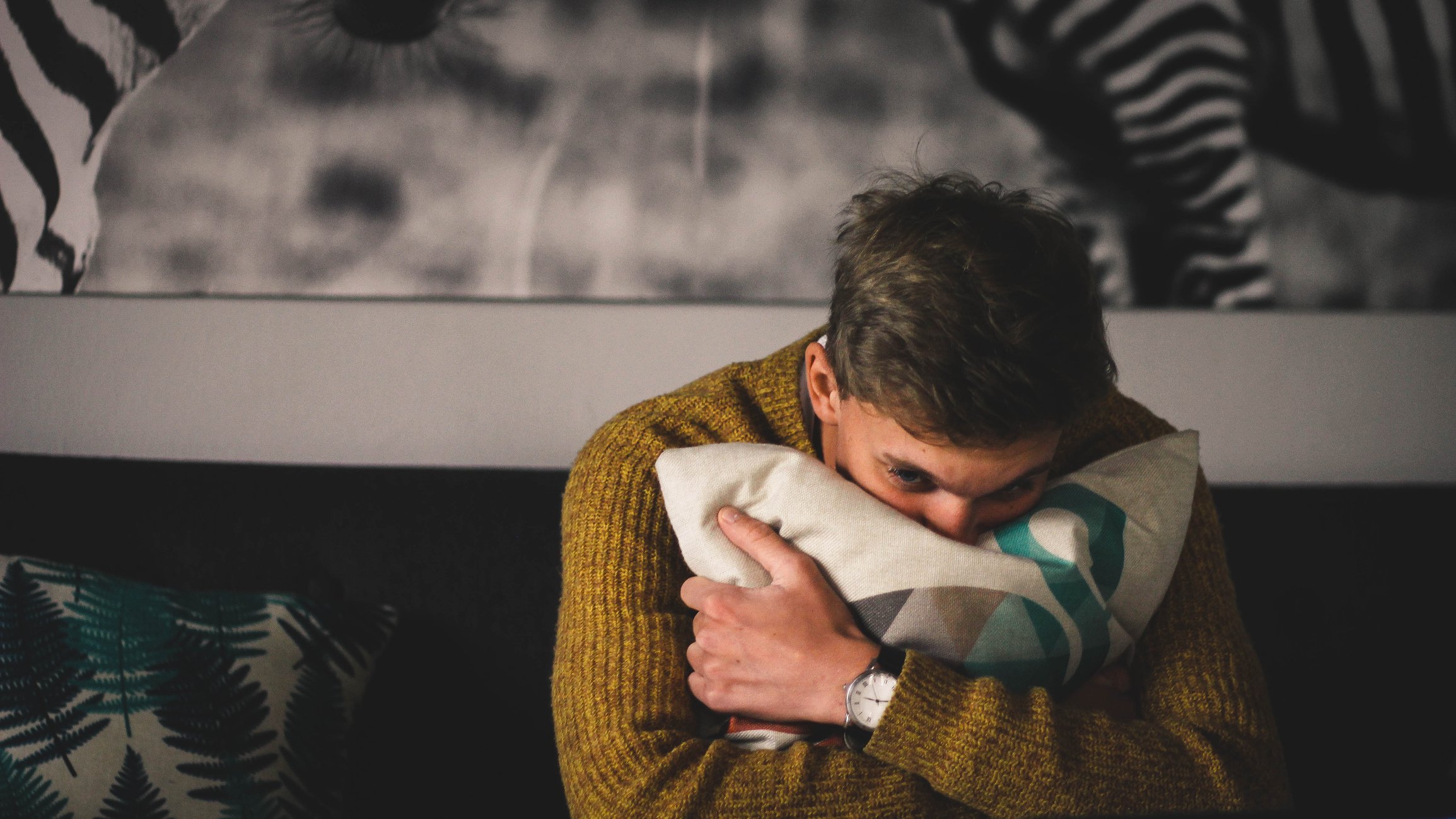 Porträt des Mannes, der ein Kissen zu Hause umarmt I Quelle: Getty Images