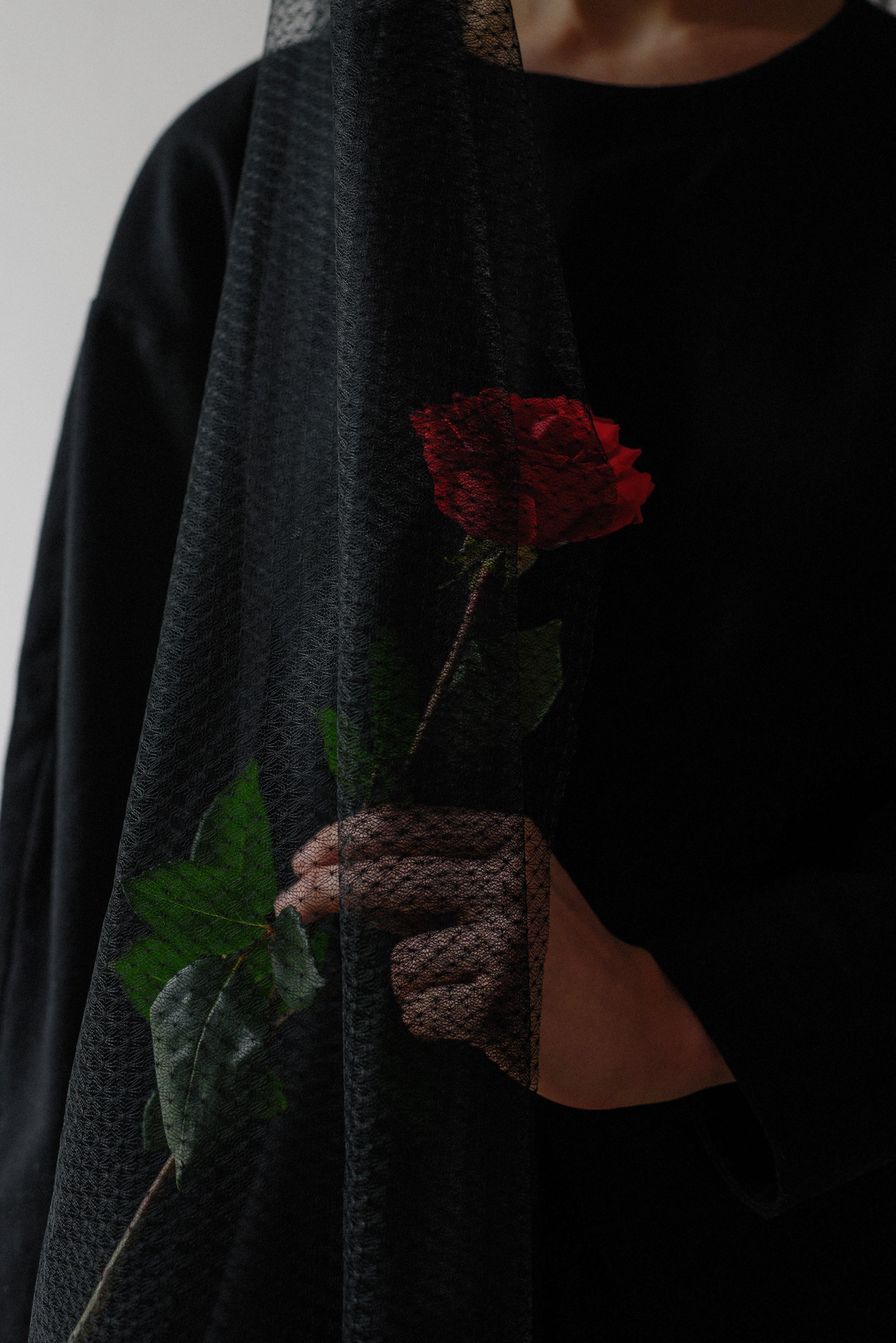 A woman covered in a black veil, holding a rose. | Source: Pexels