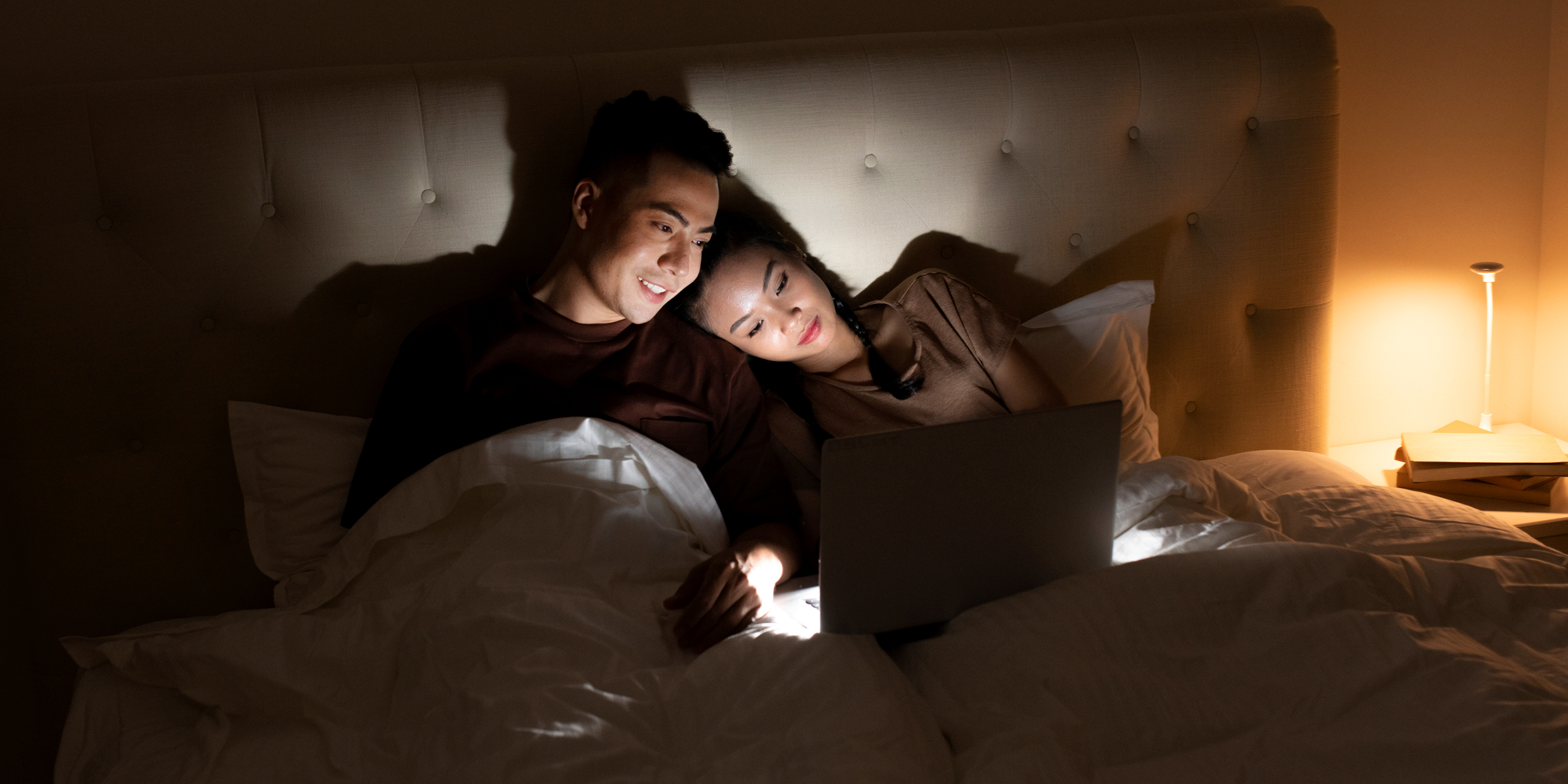 A man and woman lie in bed watching something on a laptop | Source: Freepik