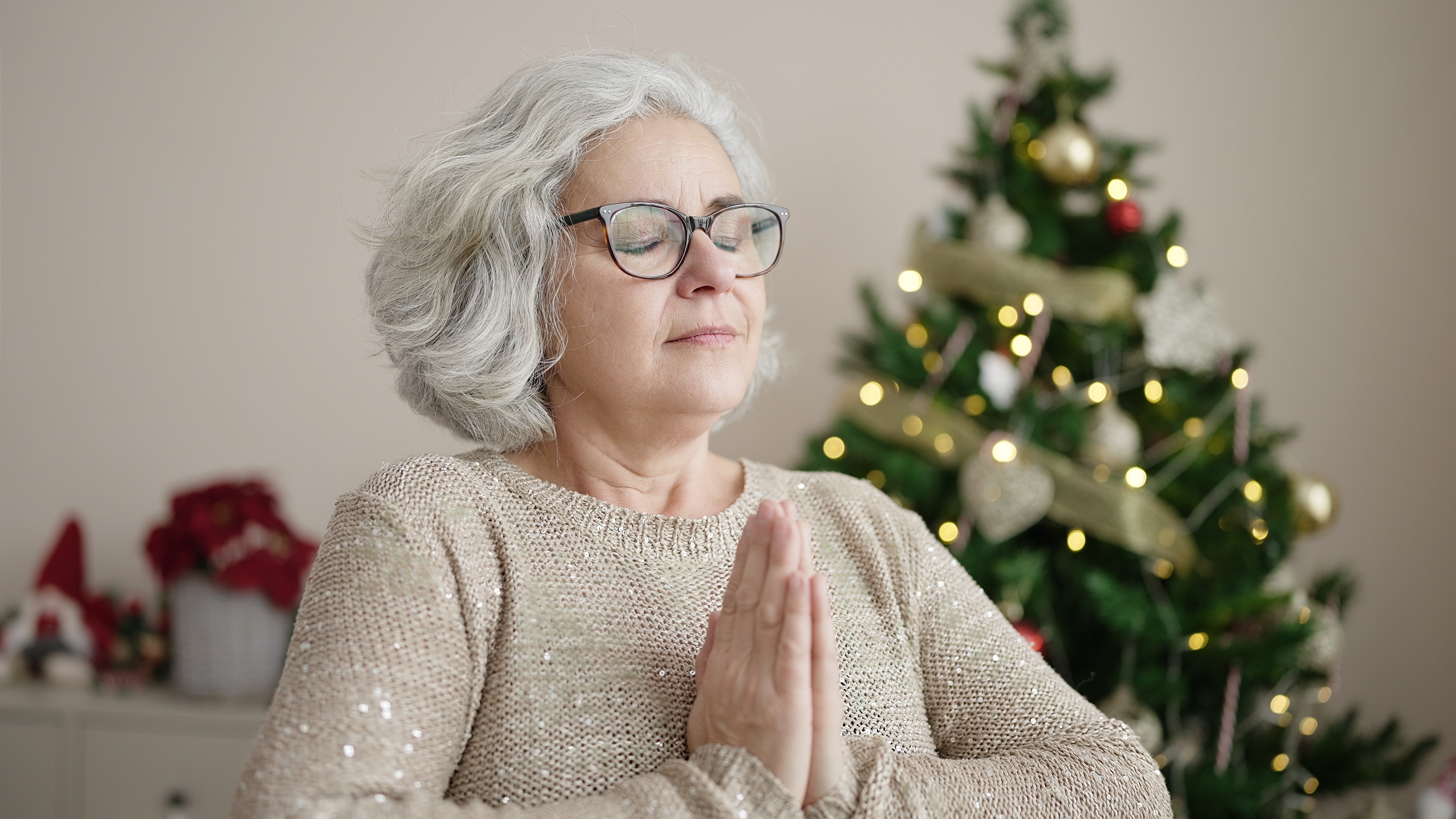 Woman meditating by the Christmas tree | Source: Shutterstock