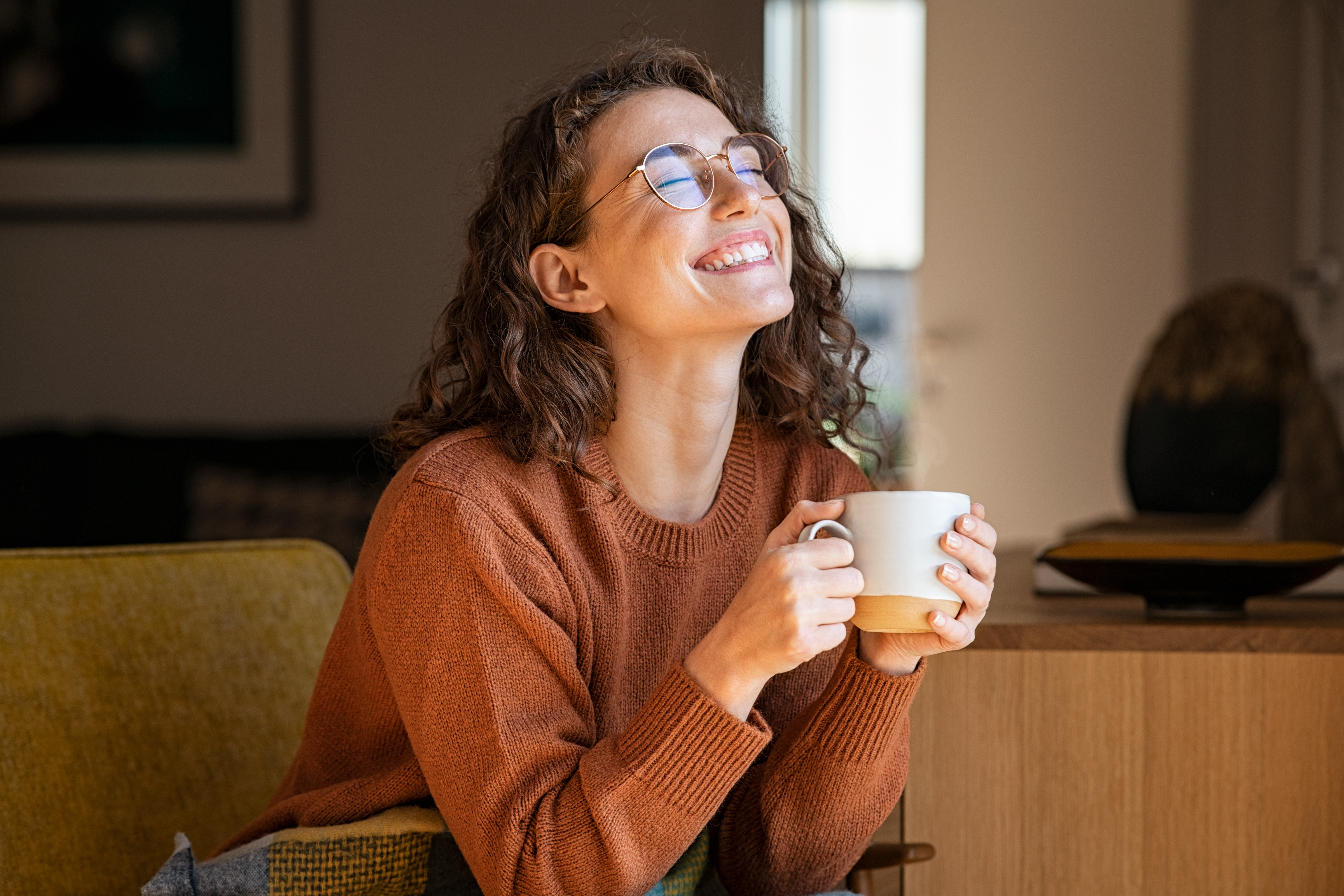Happy woman sitting with a cup | Shutterstock