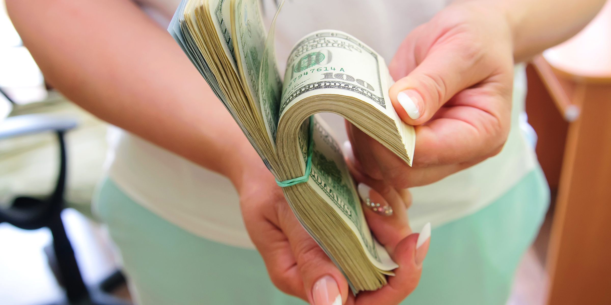 A woman holding a wad of cash | Source: Shutterstock