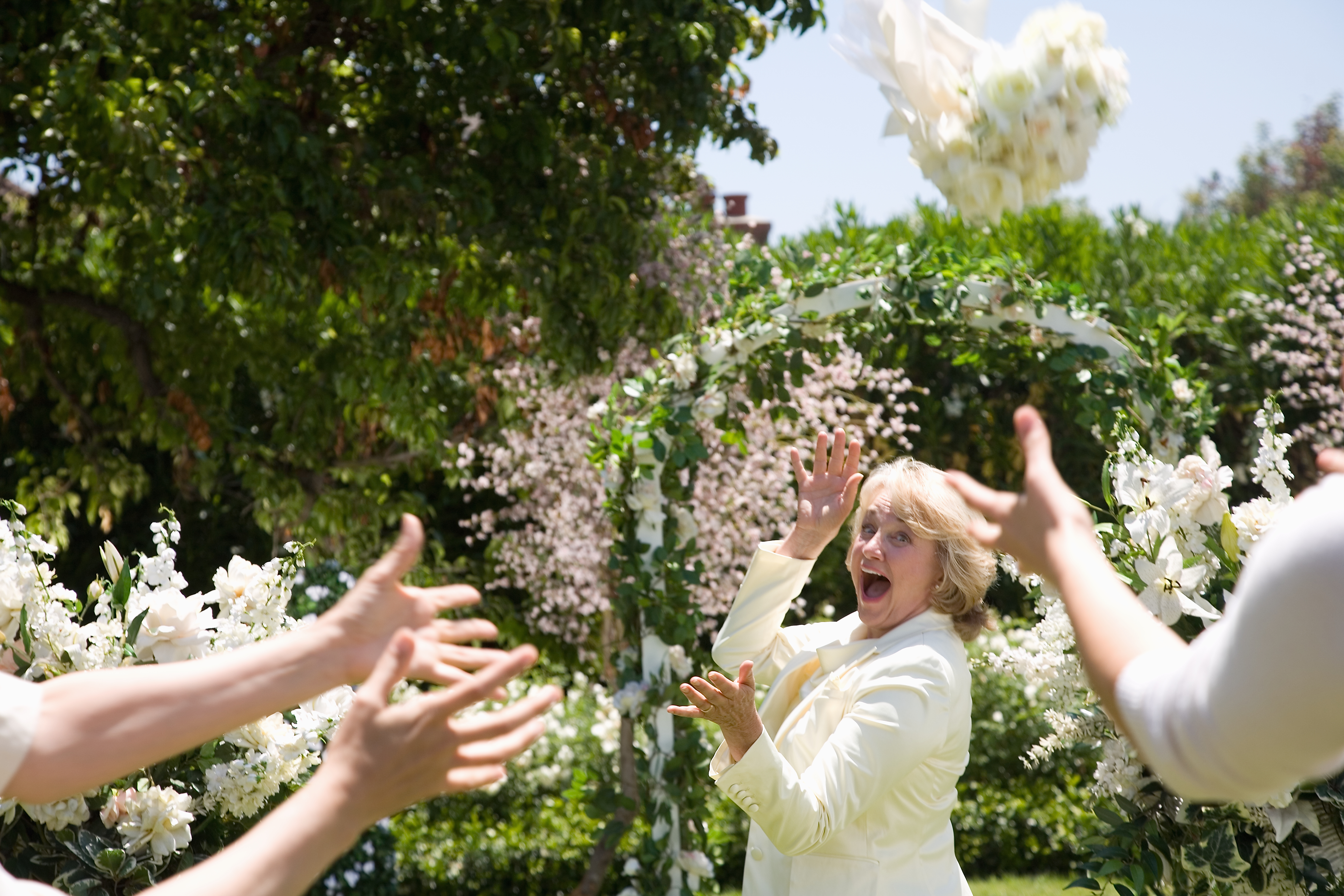 Bride throwing bouquet of flowers, laughing | Source: Getty Images