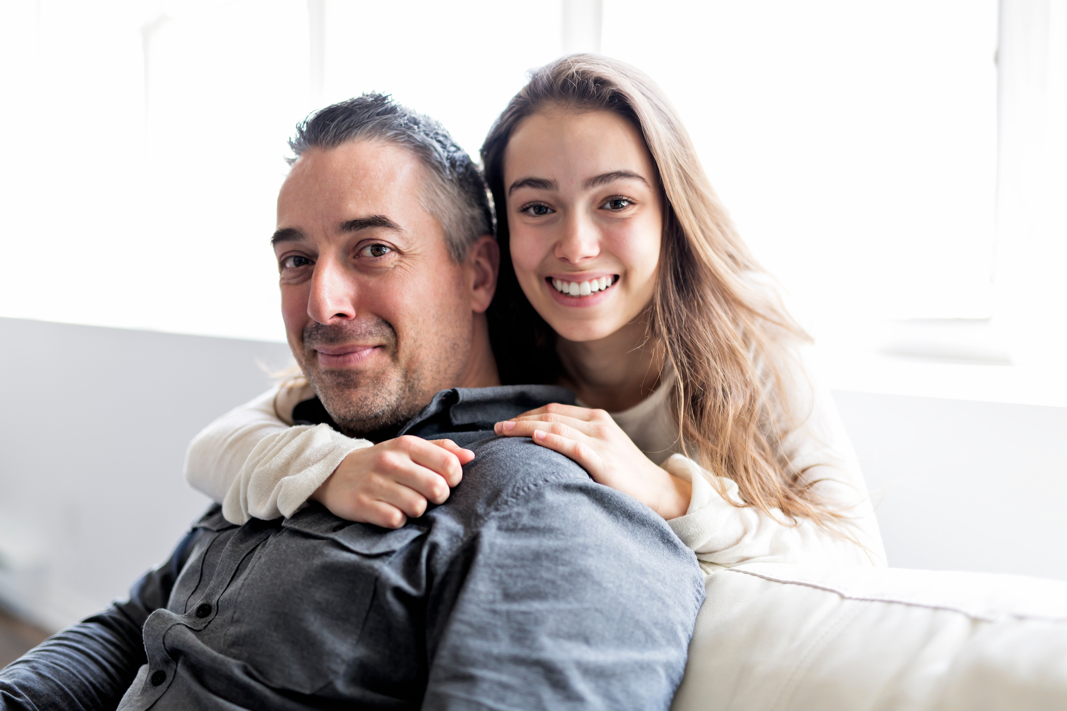 A happy teenage girl hugging her father | Source: Shutterstock