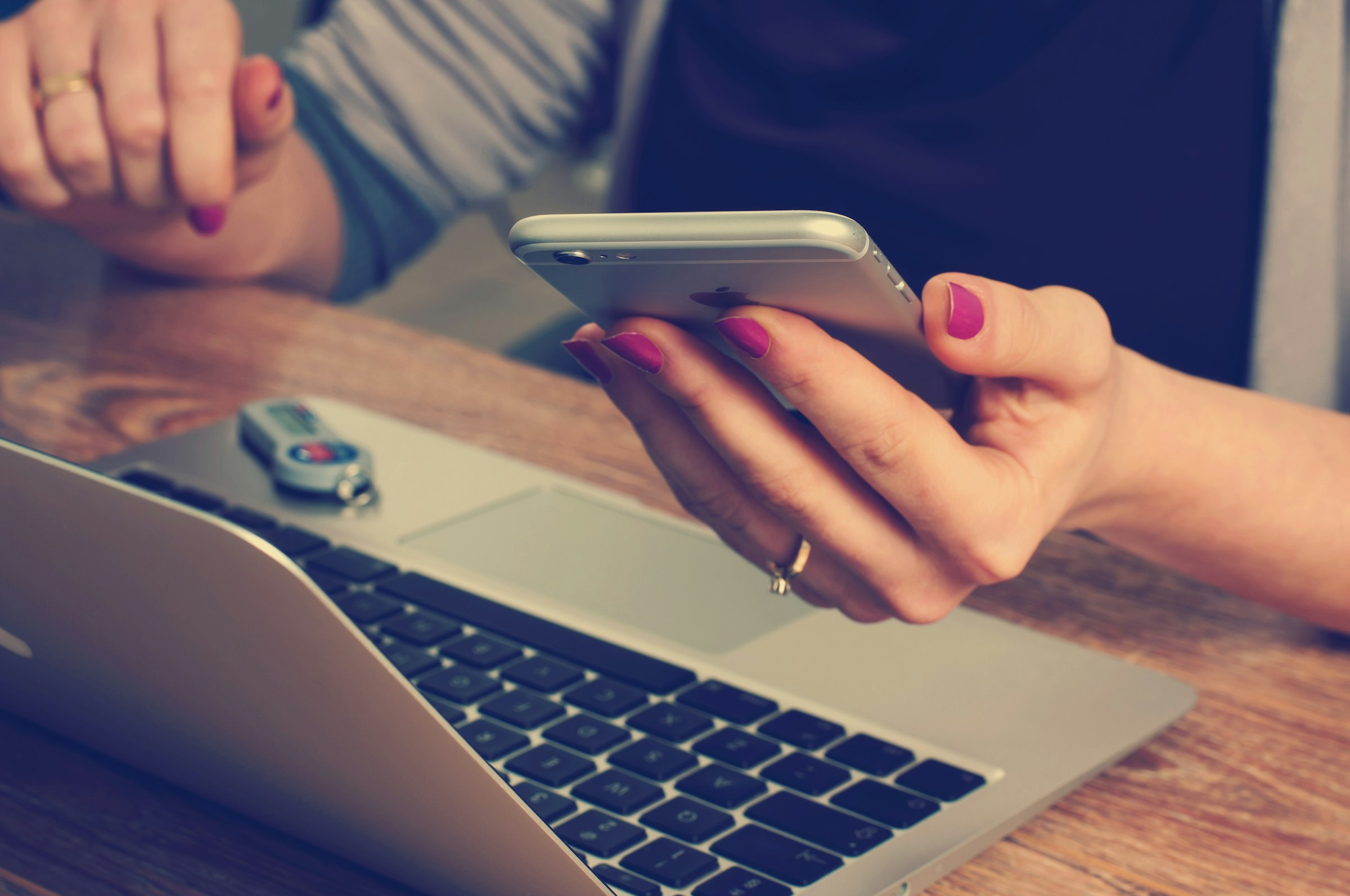 A woman checking her phone while using her laptop | Source: Unsplash