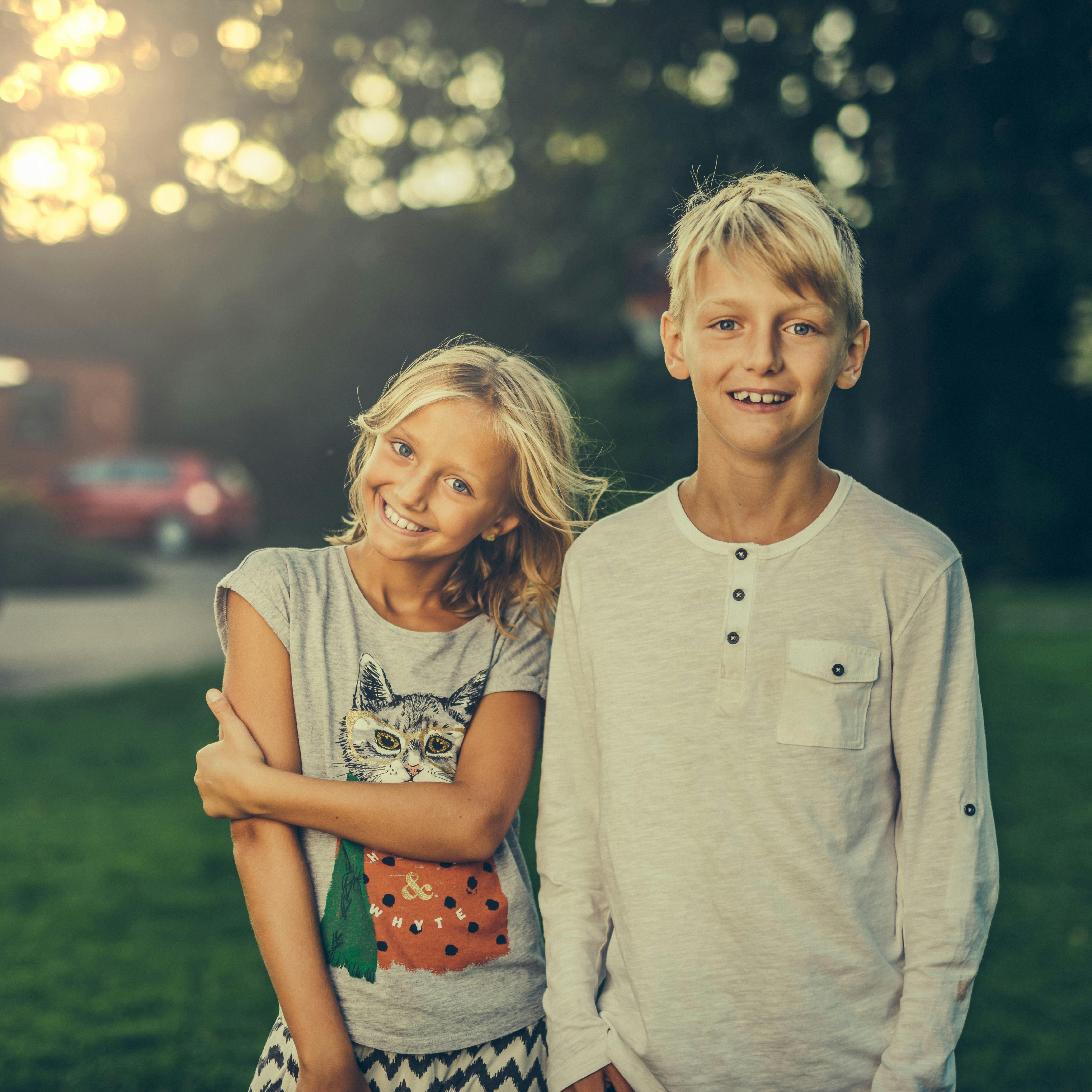 A brother and sister smiling while standing side-by-side | Source: Pexels