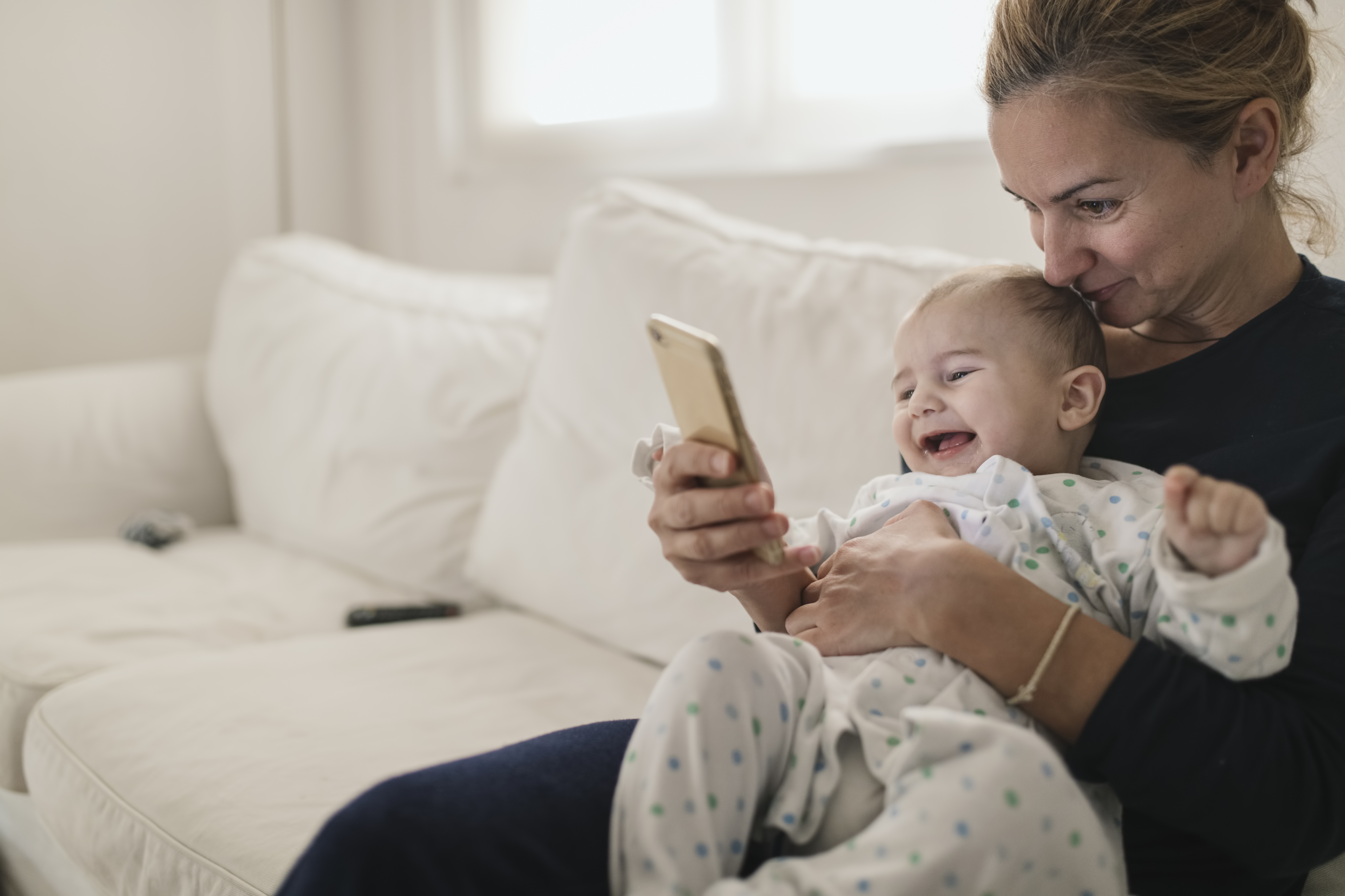 A mother is seen holding her baby while looking at her cell phone | Source: Getty Images