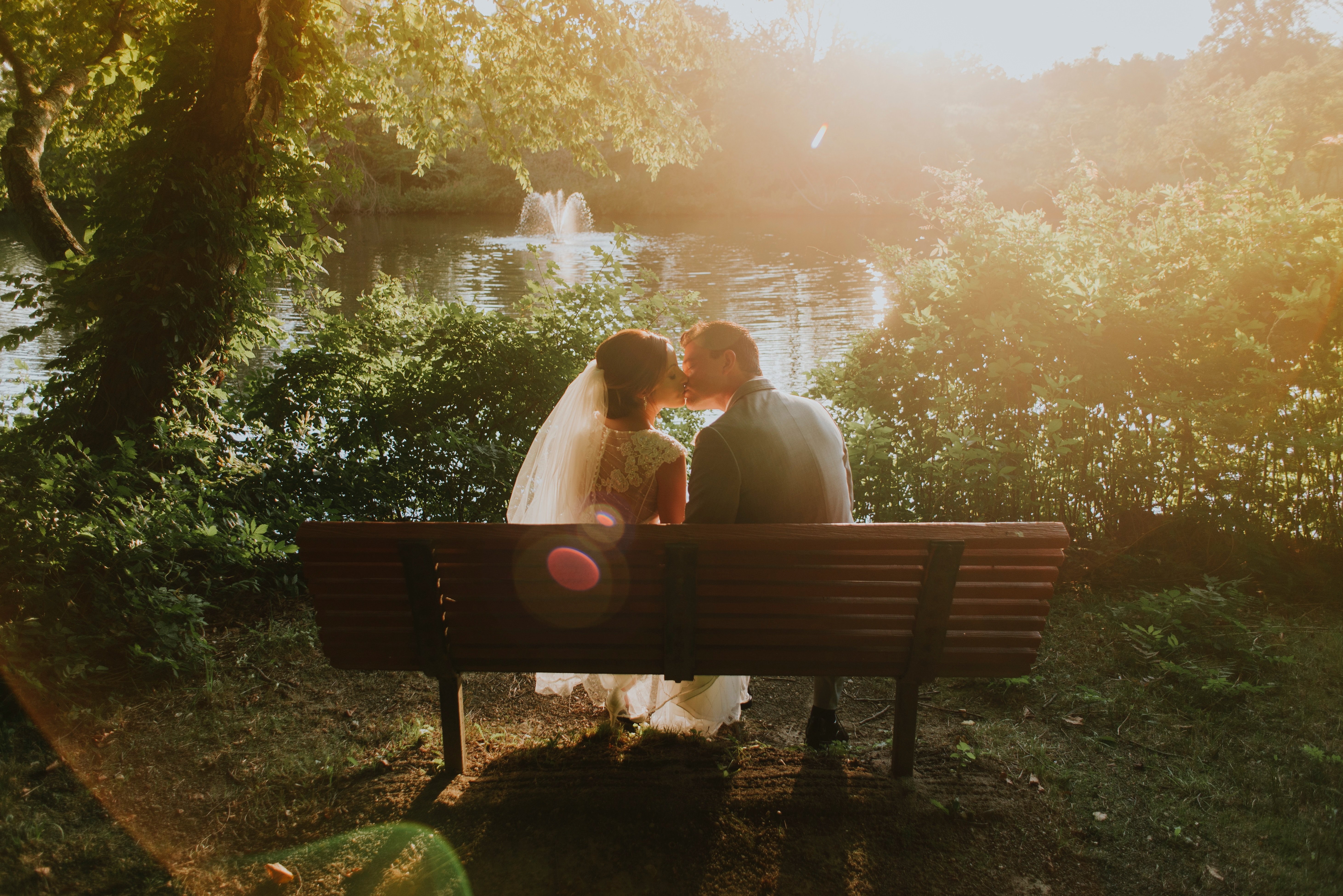 Un couple marié qui s'embrasse sur un banc. l Source: Unsplash Un couple marié qui s'embrasse sur un banc. l Source: Unsplash