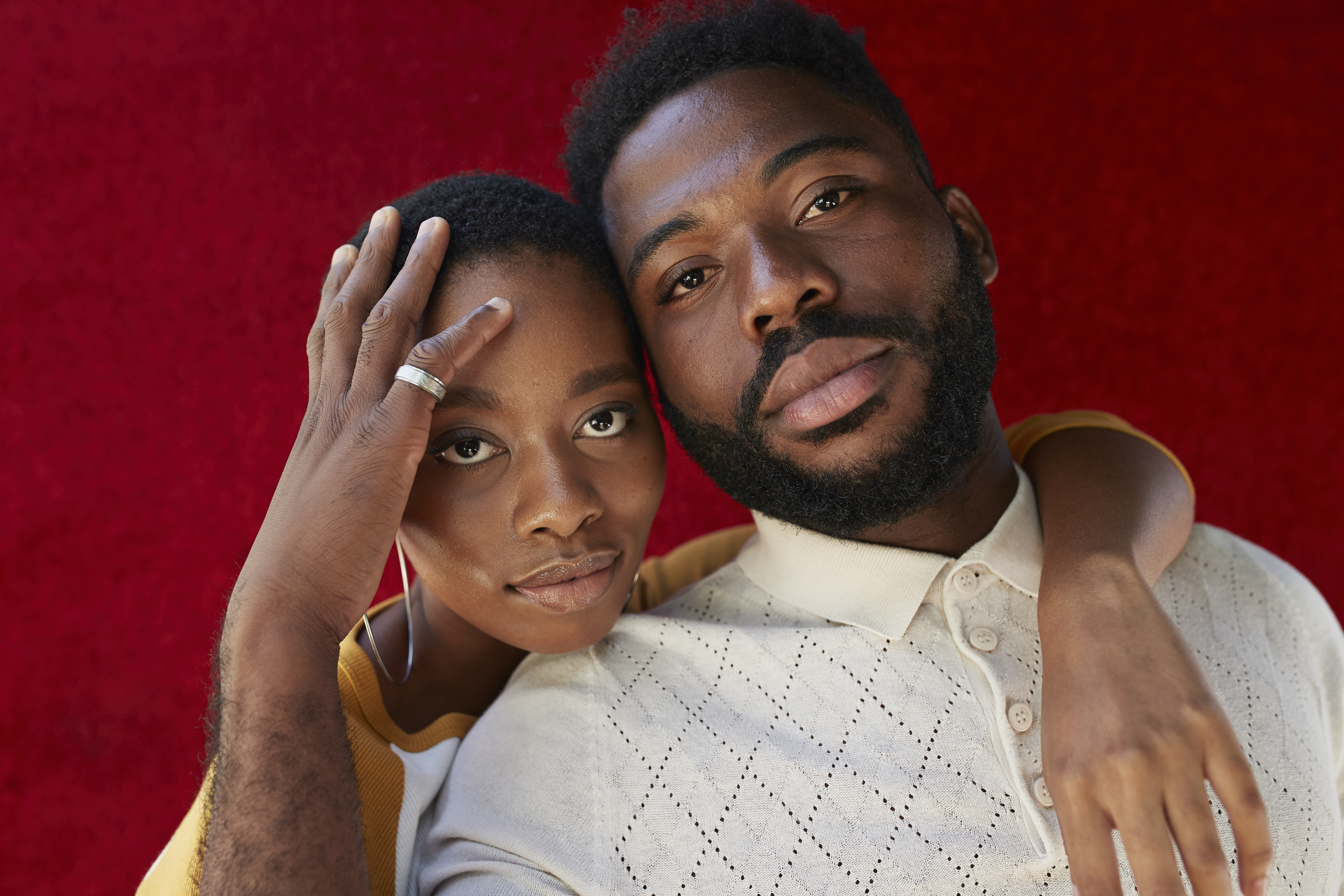 Close-up portrait of friends against red wall | Source: Getty Images