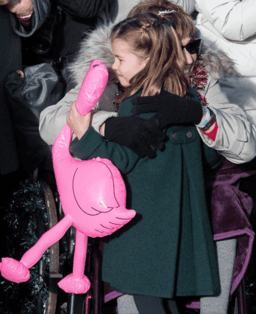 La princesse Charlotte serre dans ses bras une femme en fauteuil roulant après s'être vue offrir un flamant rose gonflable lors du service religieux du jour de Noël à l'église de St Mary Ste Marie Madeleine le 25 décembre 2019 à King's Lynn. | Source : Getty Images 