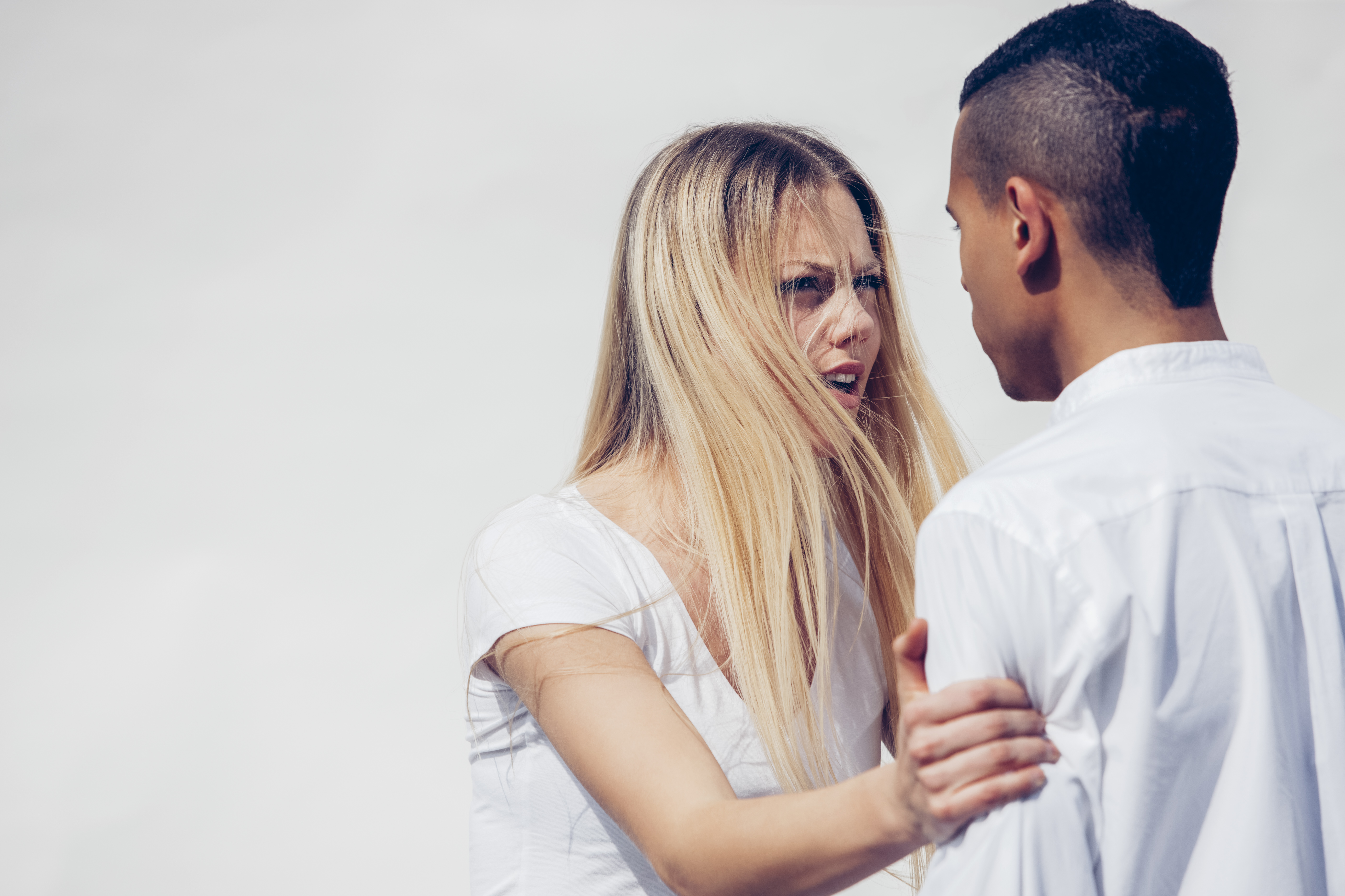 Portrait of angry young woman face to face with her boyfriend in front of white background | Source: Getty Images