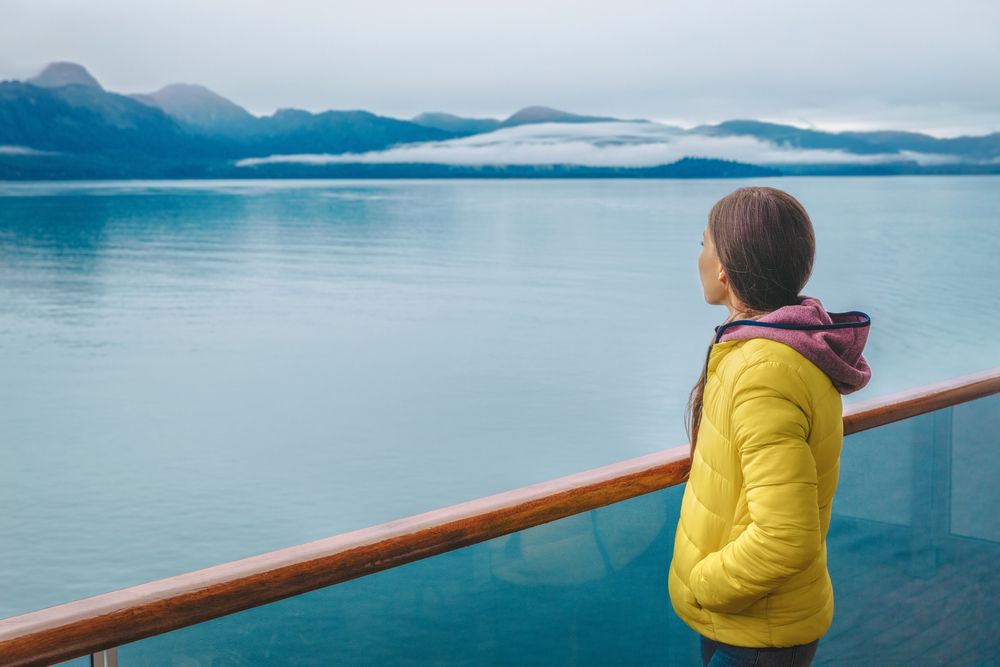 Alaska cruise tourist looking at mountains landscape. | Source: Shutterstock