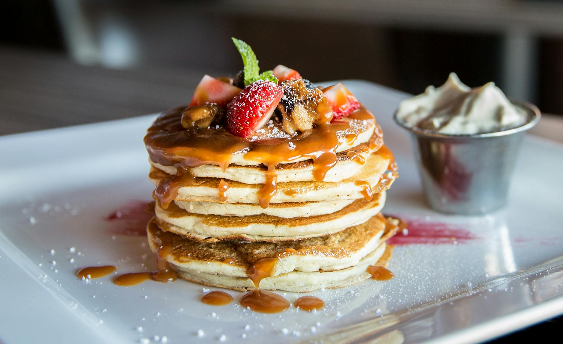 Pancakes served with sliced fruits on top and some cream | Source: Pexels