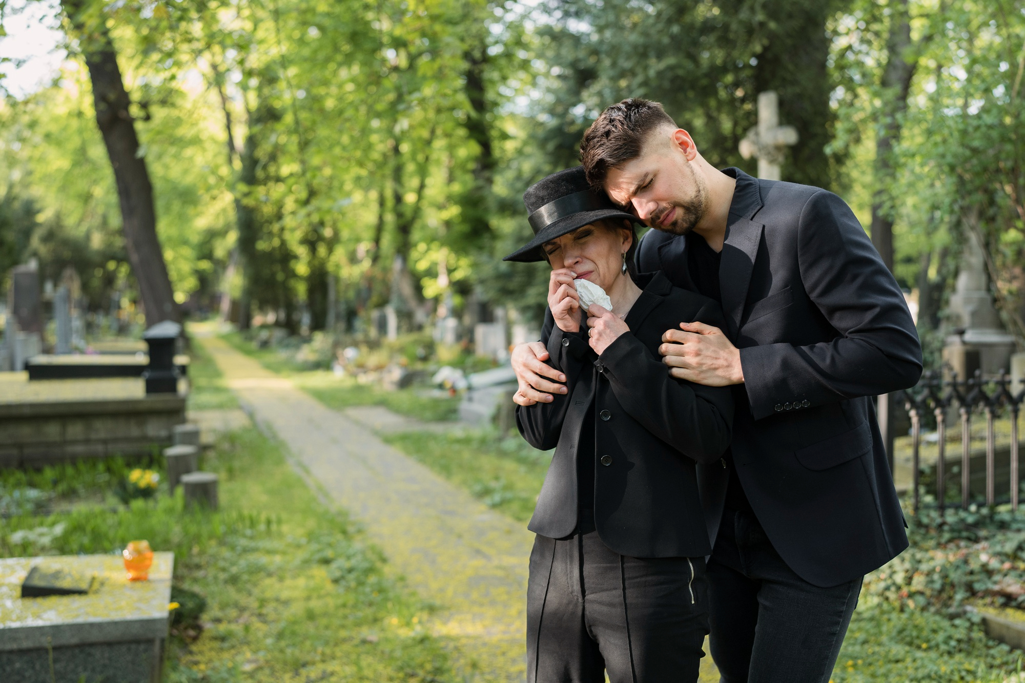 A man consoling a grieving woman in a cemetery | Source: Freepik