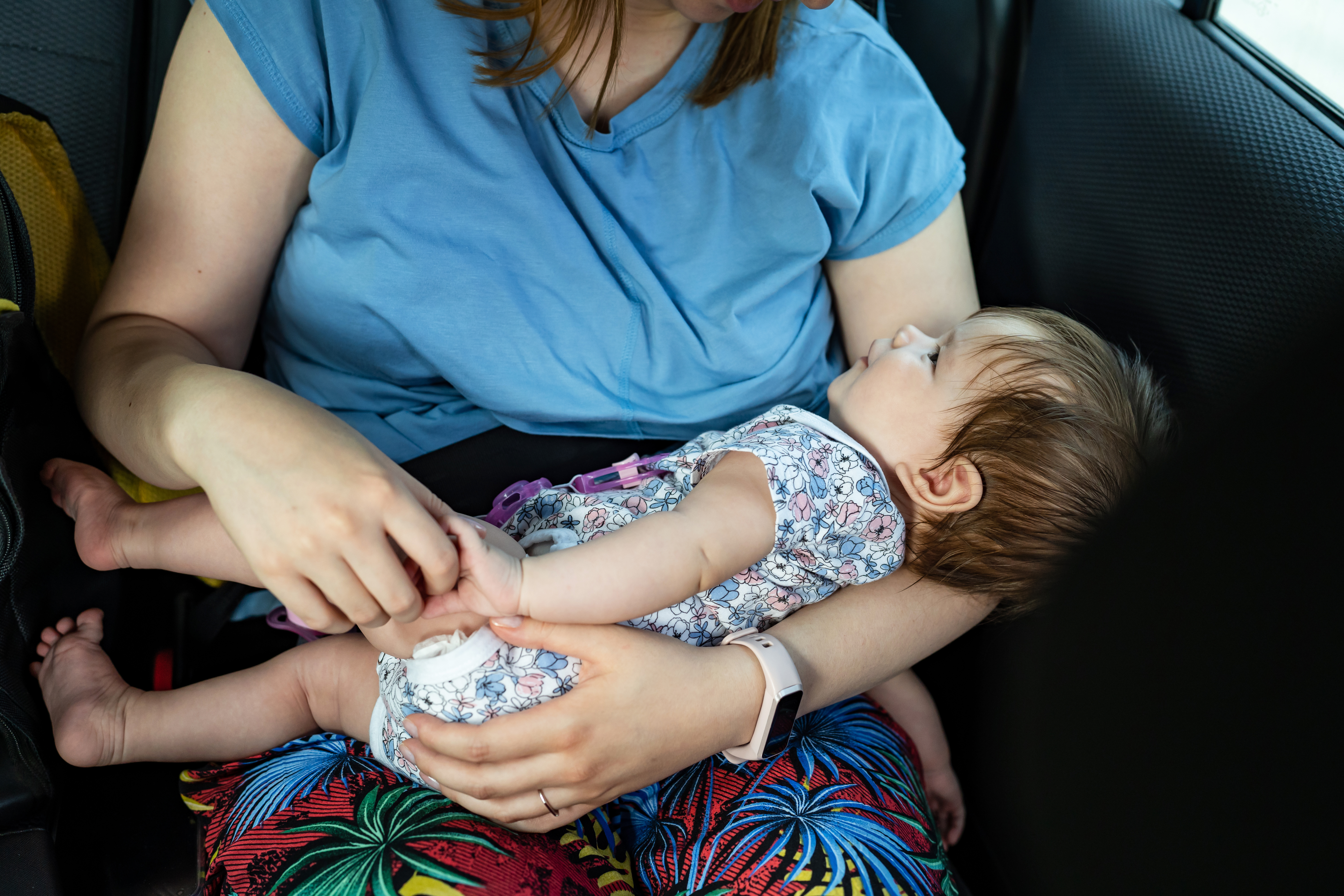 Baby four months old in the lap of her unknown mother holding her on the back seat of the car. | Source: Shutterstock