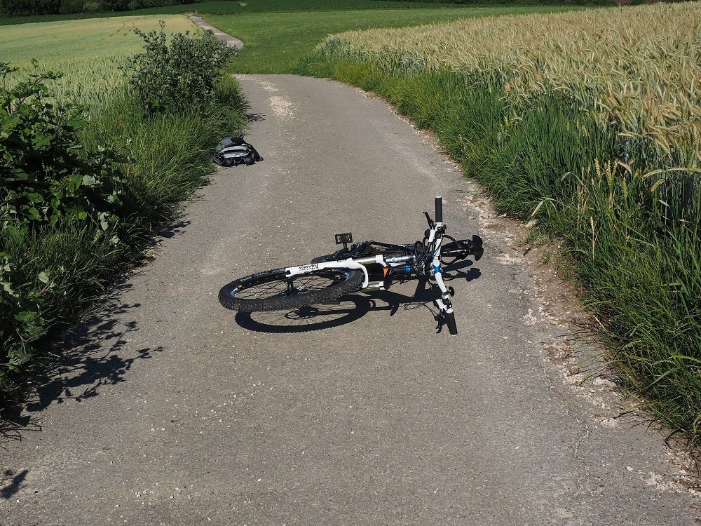A fallen, damaged bicycle on a paved road. | Image: Pixabay.