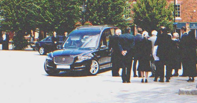 Personas reunidas cerca de un carro fúnebre. | Foto: Shutterstock