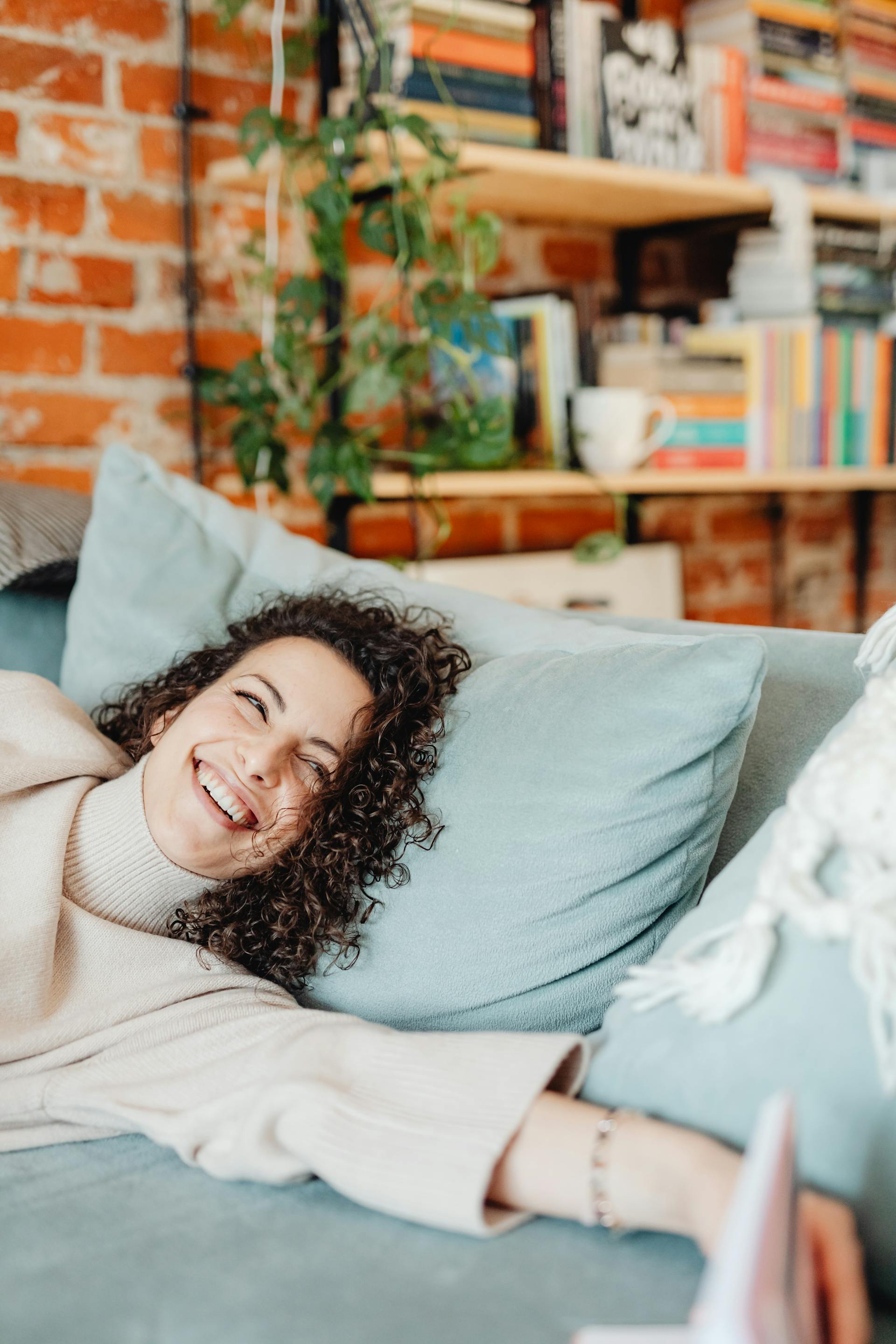 A happy woman lying on a couch with a smile on her face | Source: Pexels