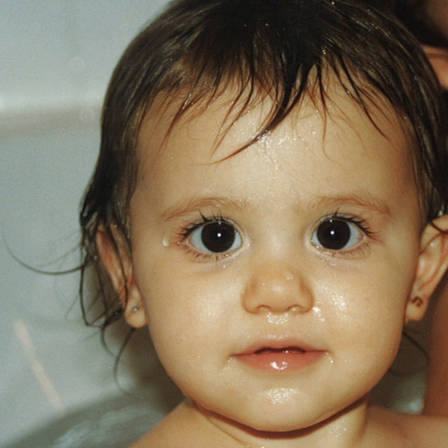 A young Ariana Grande fresh from a bath, water droplets still on her cheeks, gazing up with those expressive eyes | Source: Instagram/arianagrande
