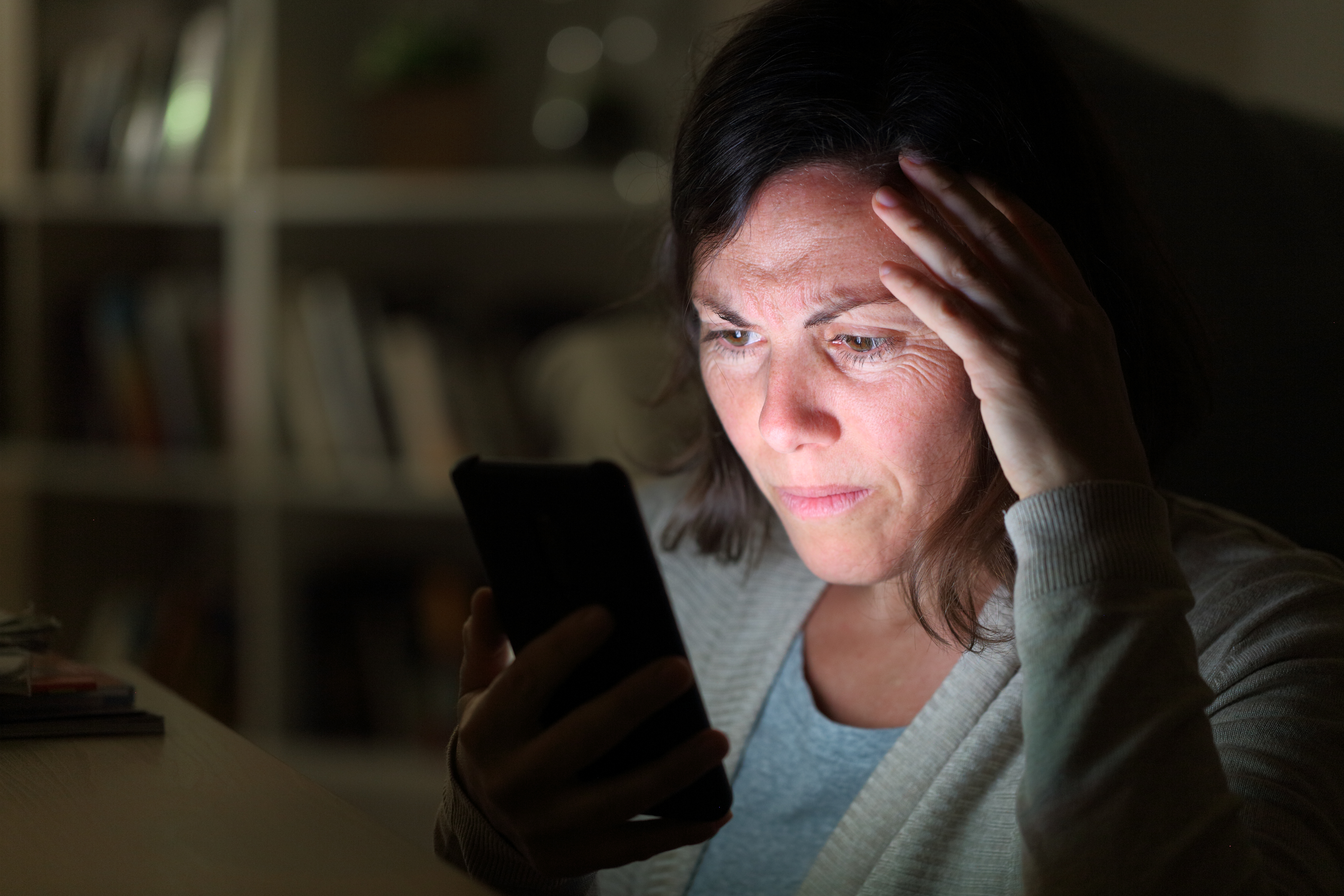 A concerned woman is looking at her cell | Source: Shutterstock