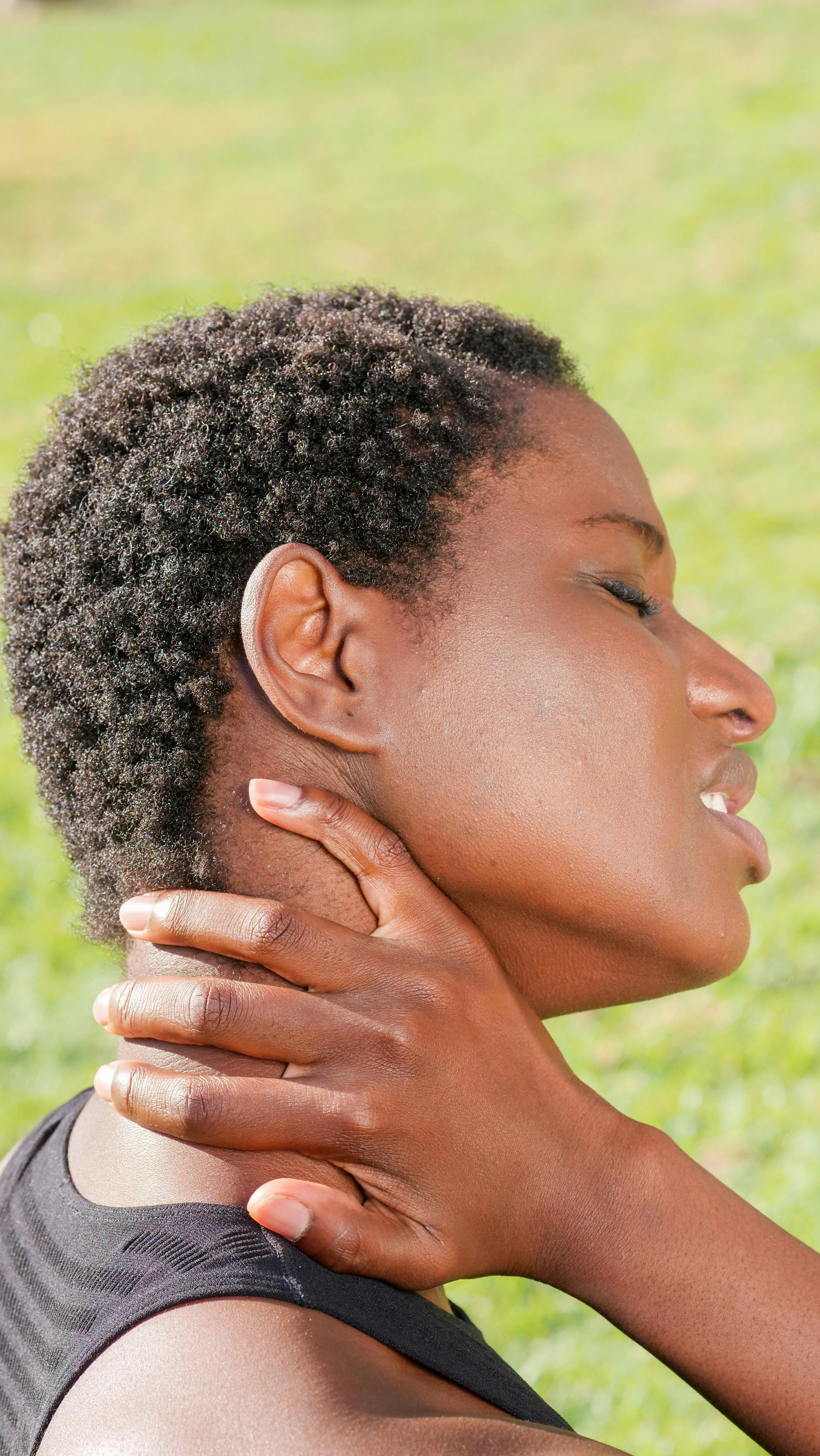 A woman holding her neck in pain after a workout. | Source: Pexels