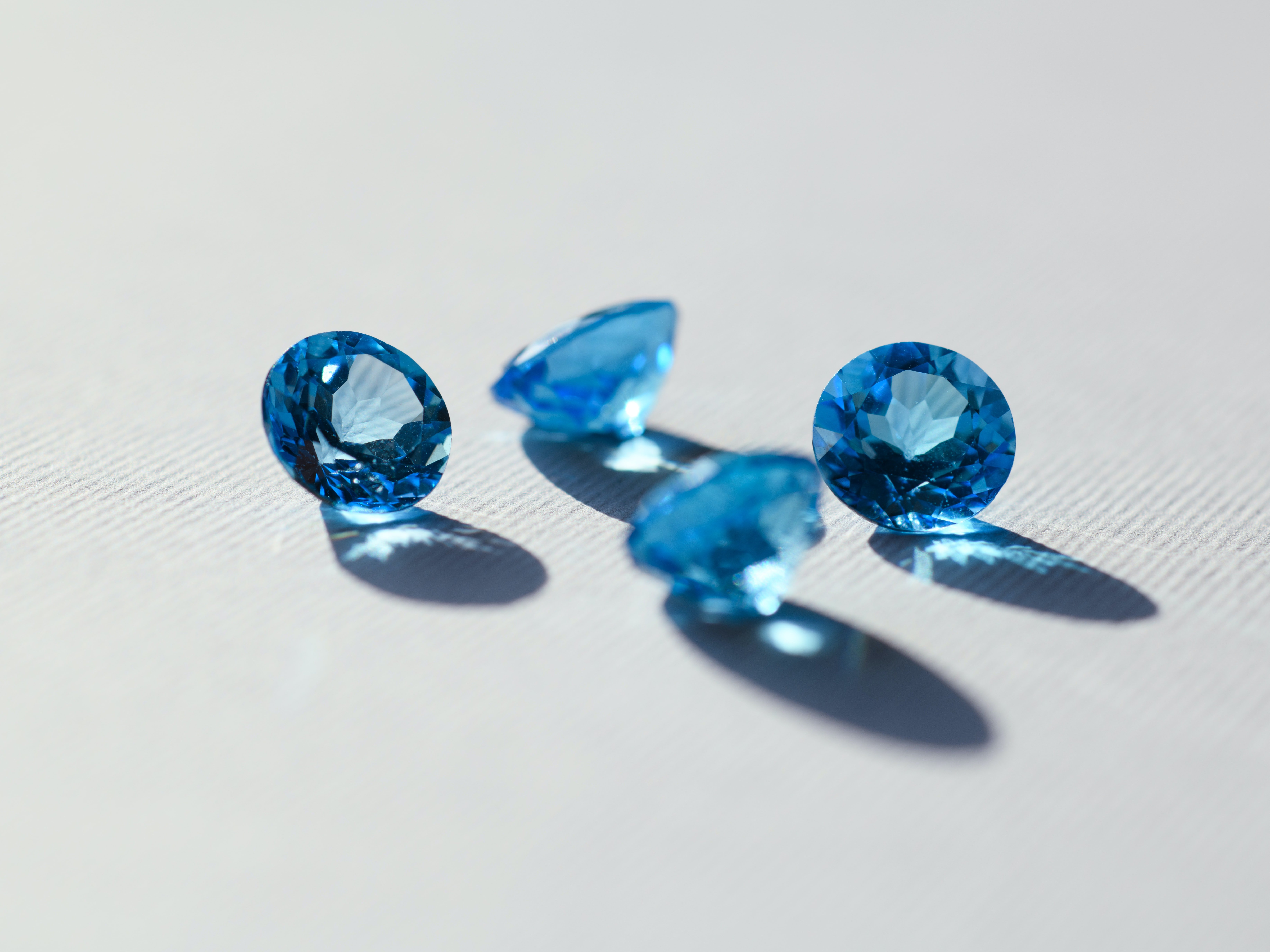 Blue sapphire gems are scattered on a white surface | Photo: Unsplash/Jacek Dylag 