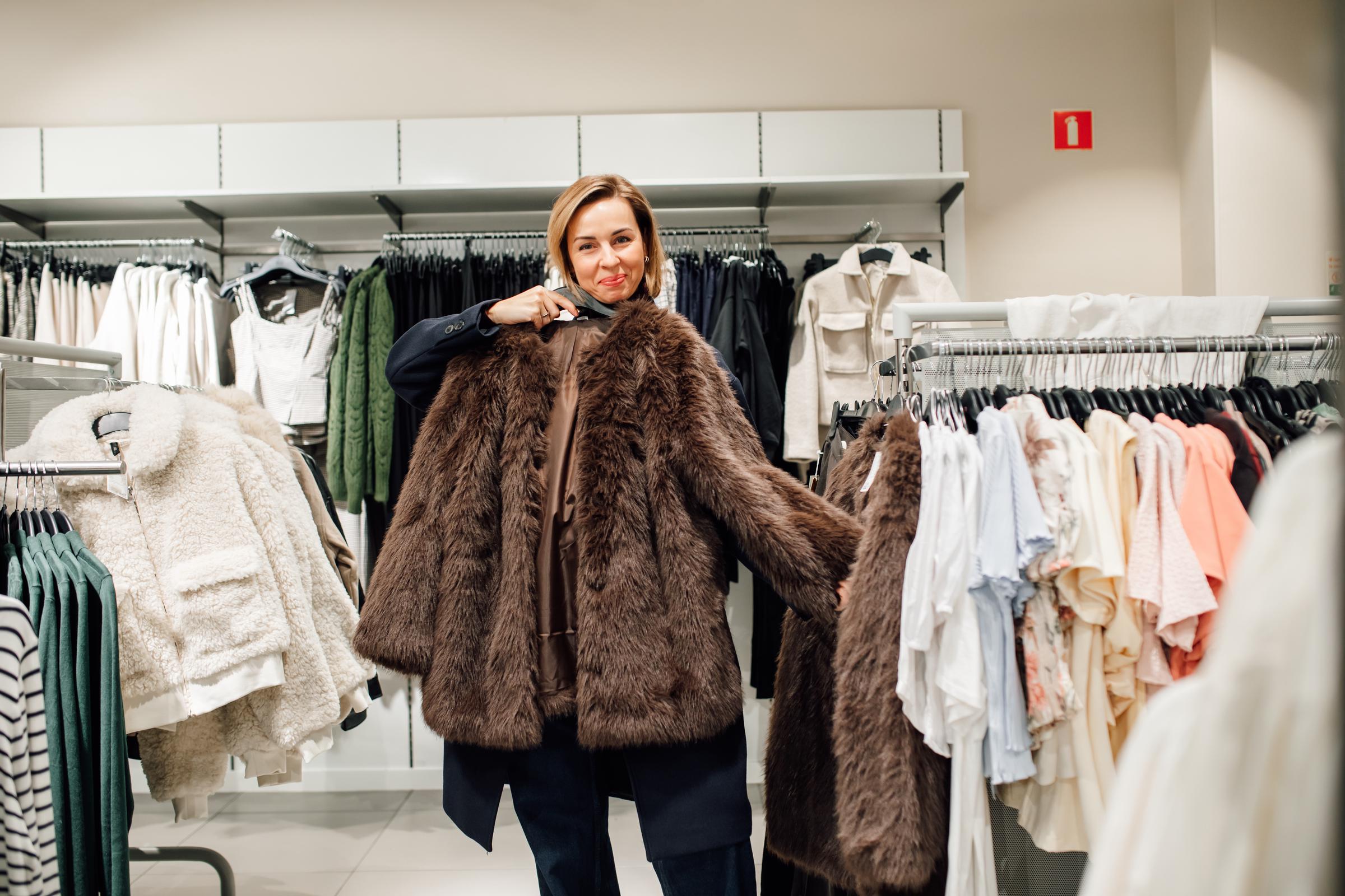 A woman holding a large, brown fur coat | Source: Getty Images