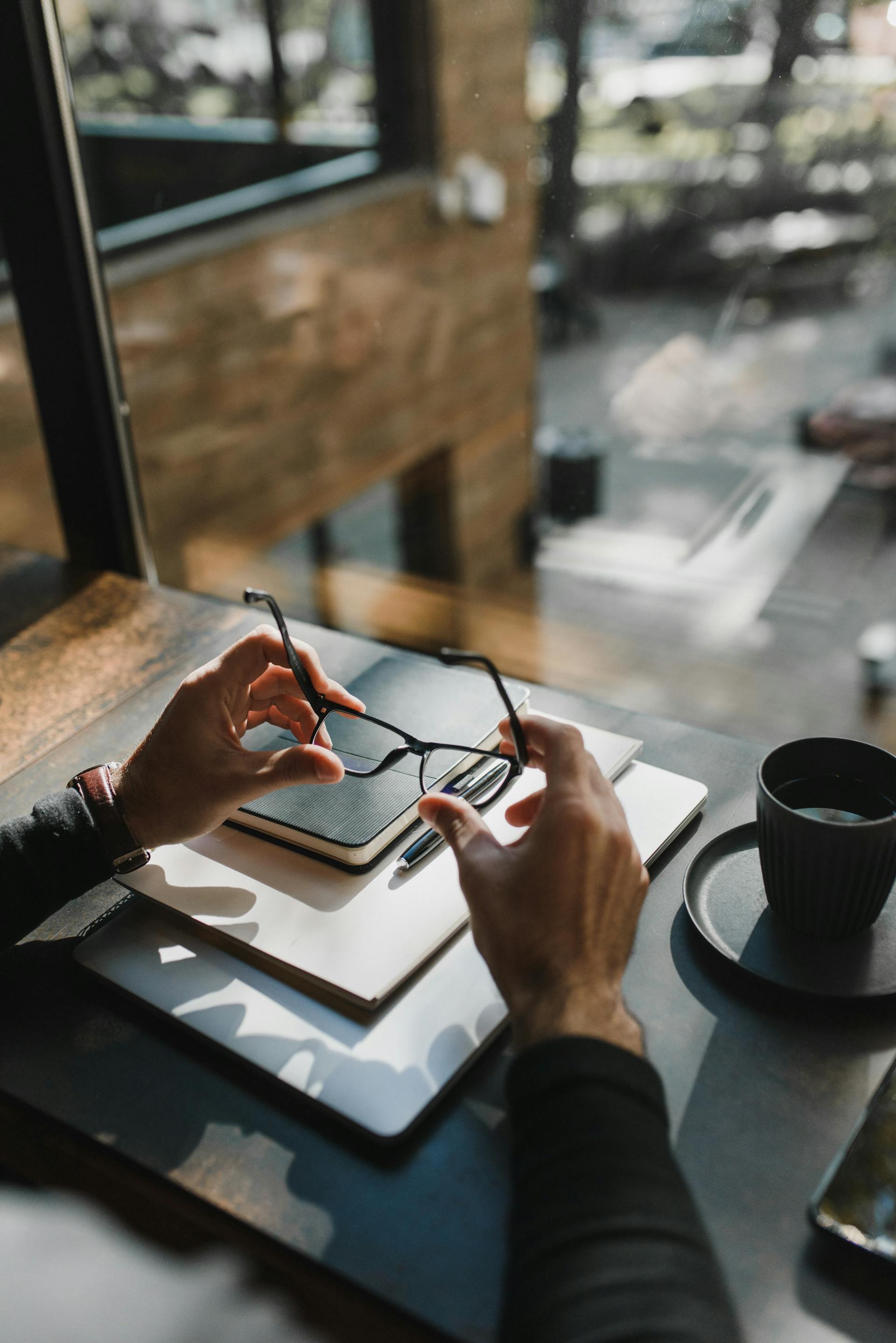 Close-up shot of a man holding his eyeglasses while sitting in his home office | Source: Pexels