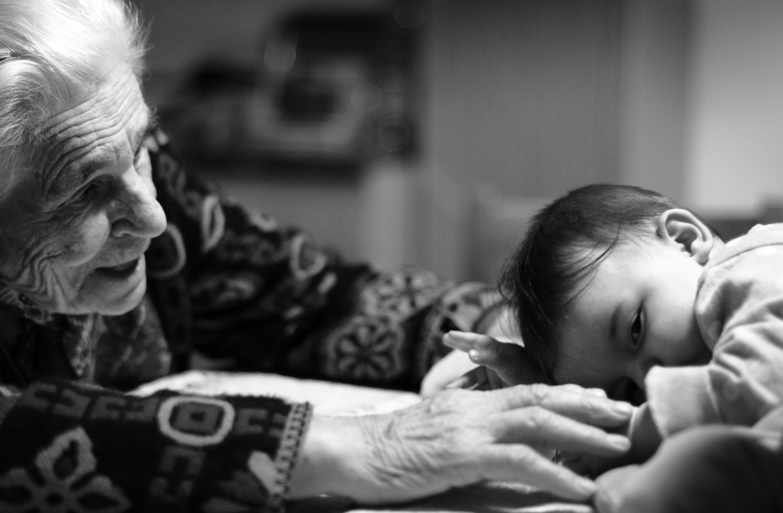 A grayscale picture of an older woman watching a baby. | Source: Unsplash
