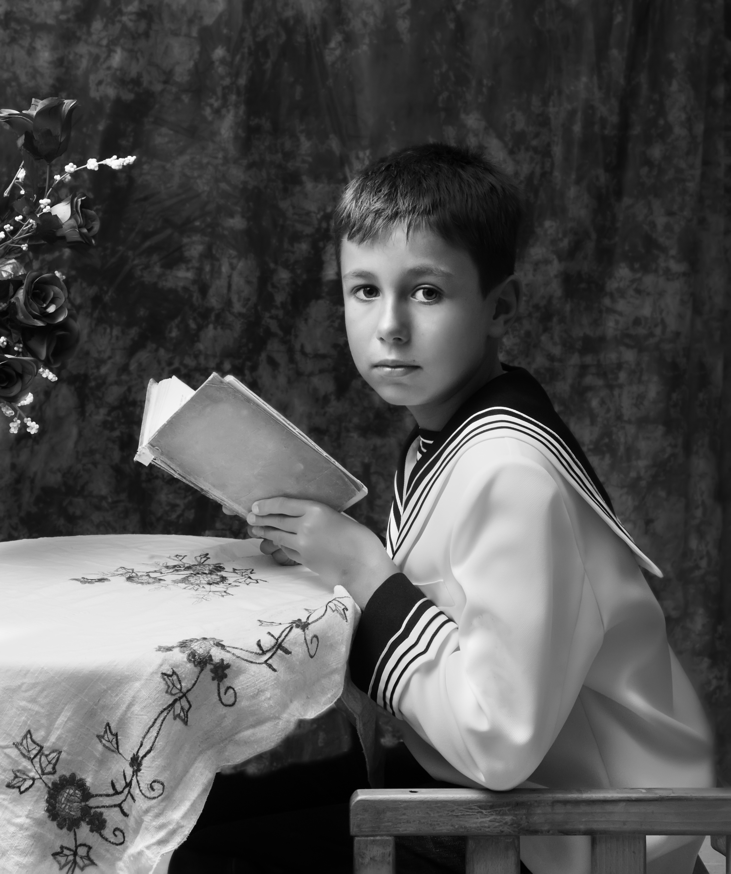 A boy sitting at a table holding a book | Source: Shutterstock