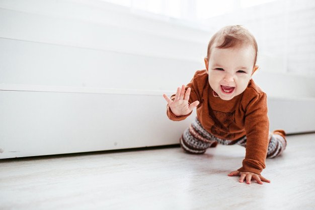 Fröhliches Kind krabbelt auf dem Boden - Quelle: Shutterstock