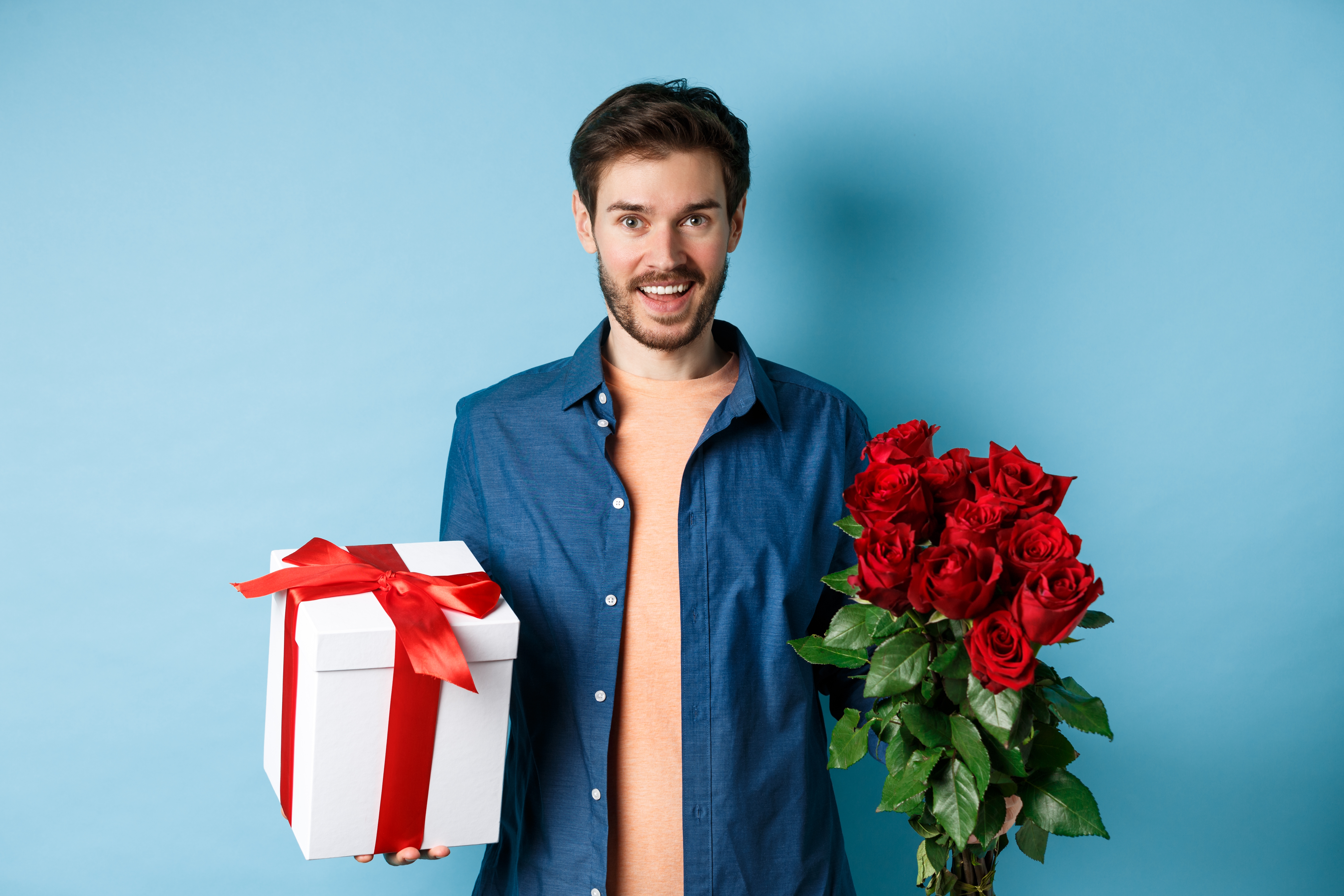 Happy young man bring flowers and gift on romantic date. | Source: Shutterstock