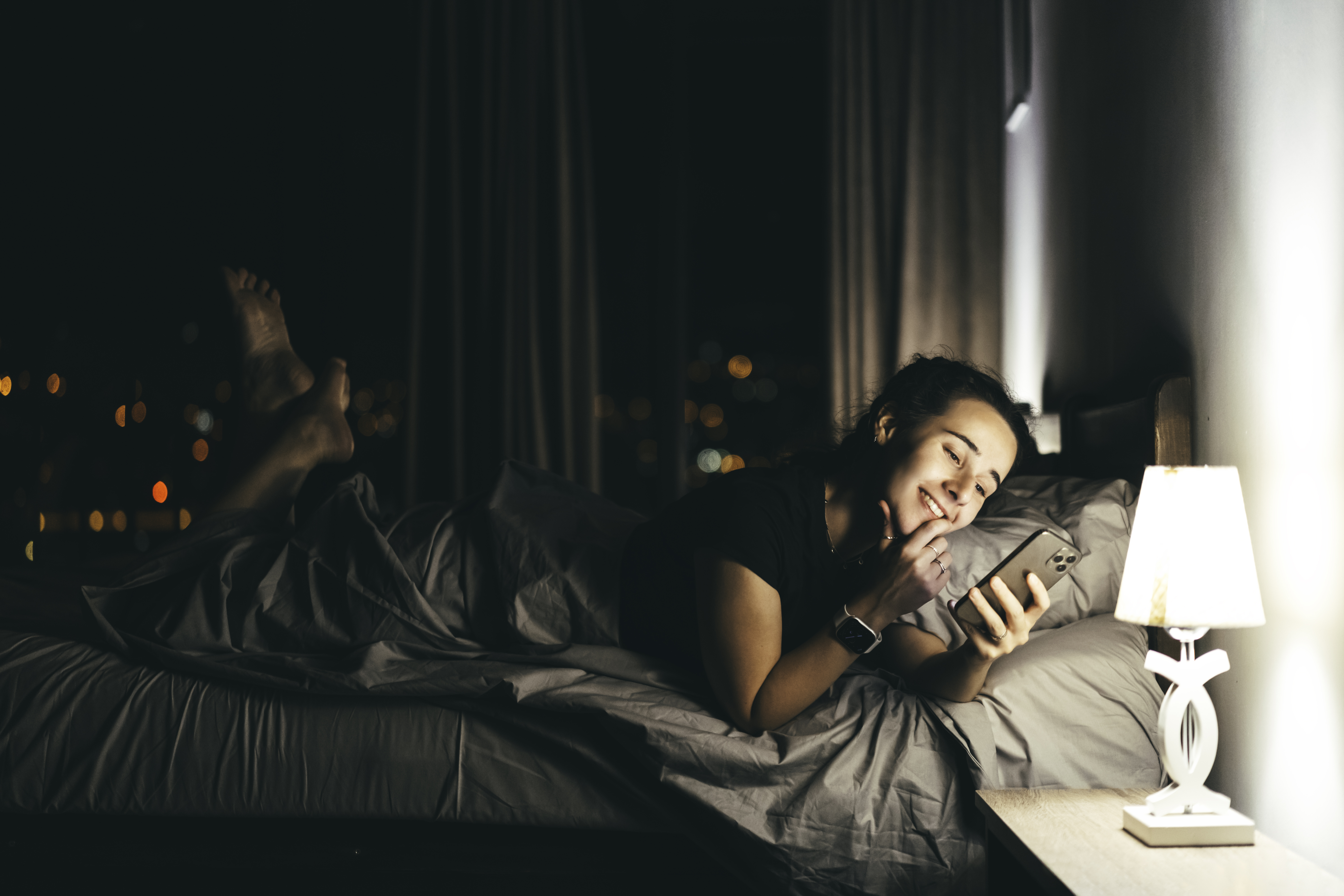 Happy person lying in bed holding their phone | Source: Getty Images