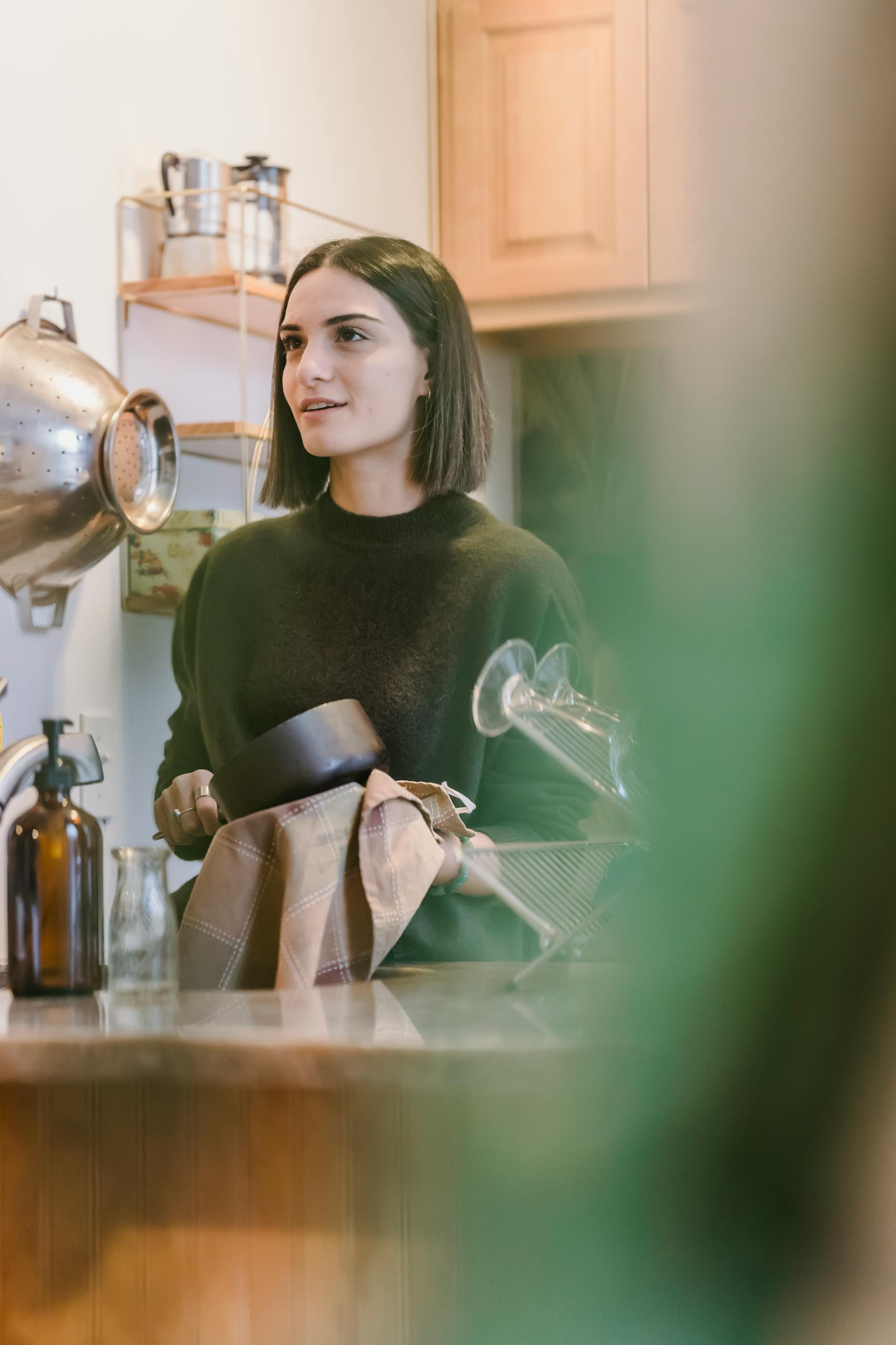 A woman drying utensils with a towel in the kitchen | Source: Pexels