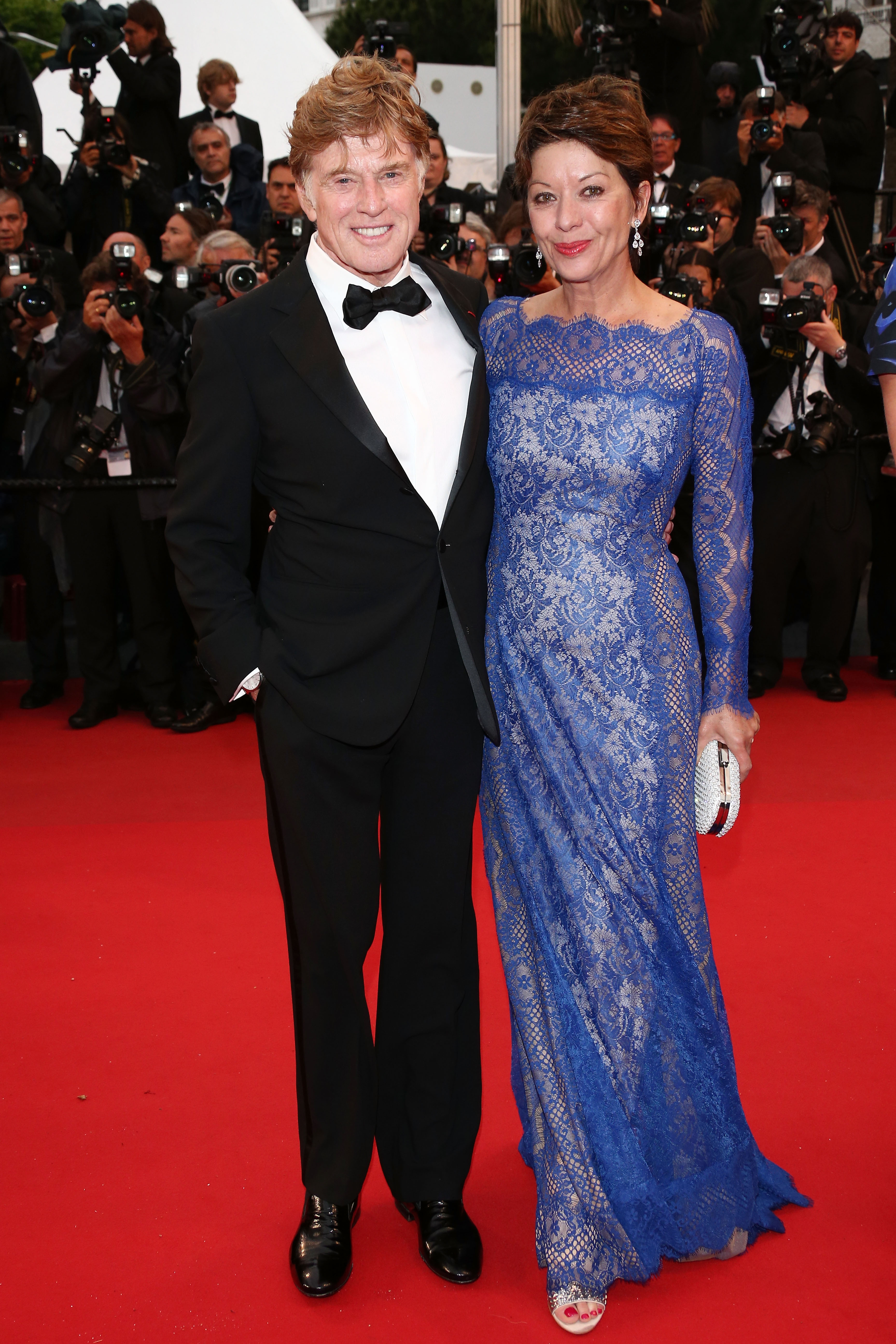 On May 22, the couple attends the "All Is Lost" premiere during the 66th Cannes Film Festival. Szaggars wears a floor-length blue lace gown with sheer sleeves, drop earrings, and a white clutch. Redford wears a black tuxedo with a white shirt and black bow tie. They pose together on the red carpet.