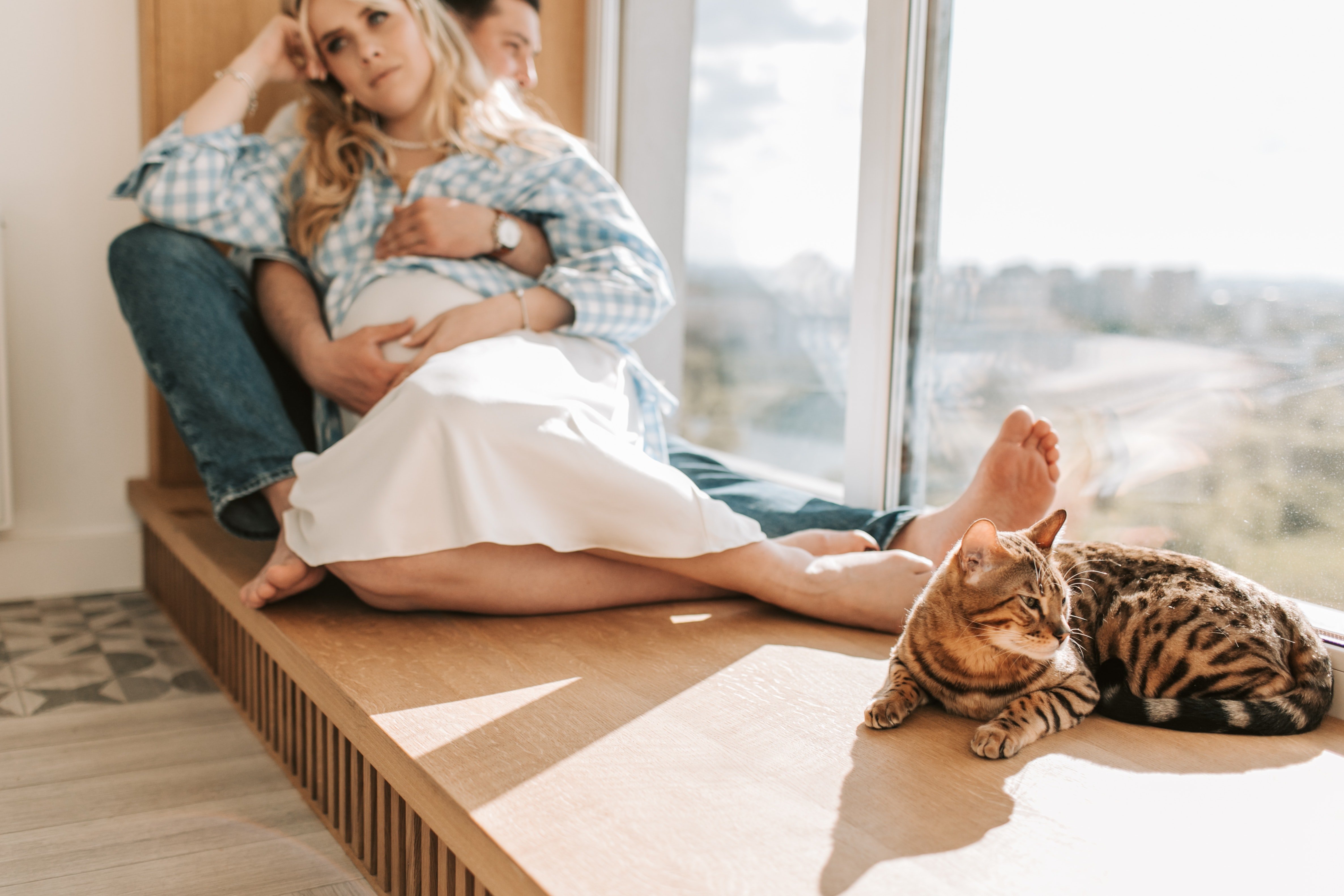 Couple relaxing by the window with their pet cat | Photo: Pexels