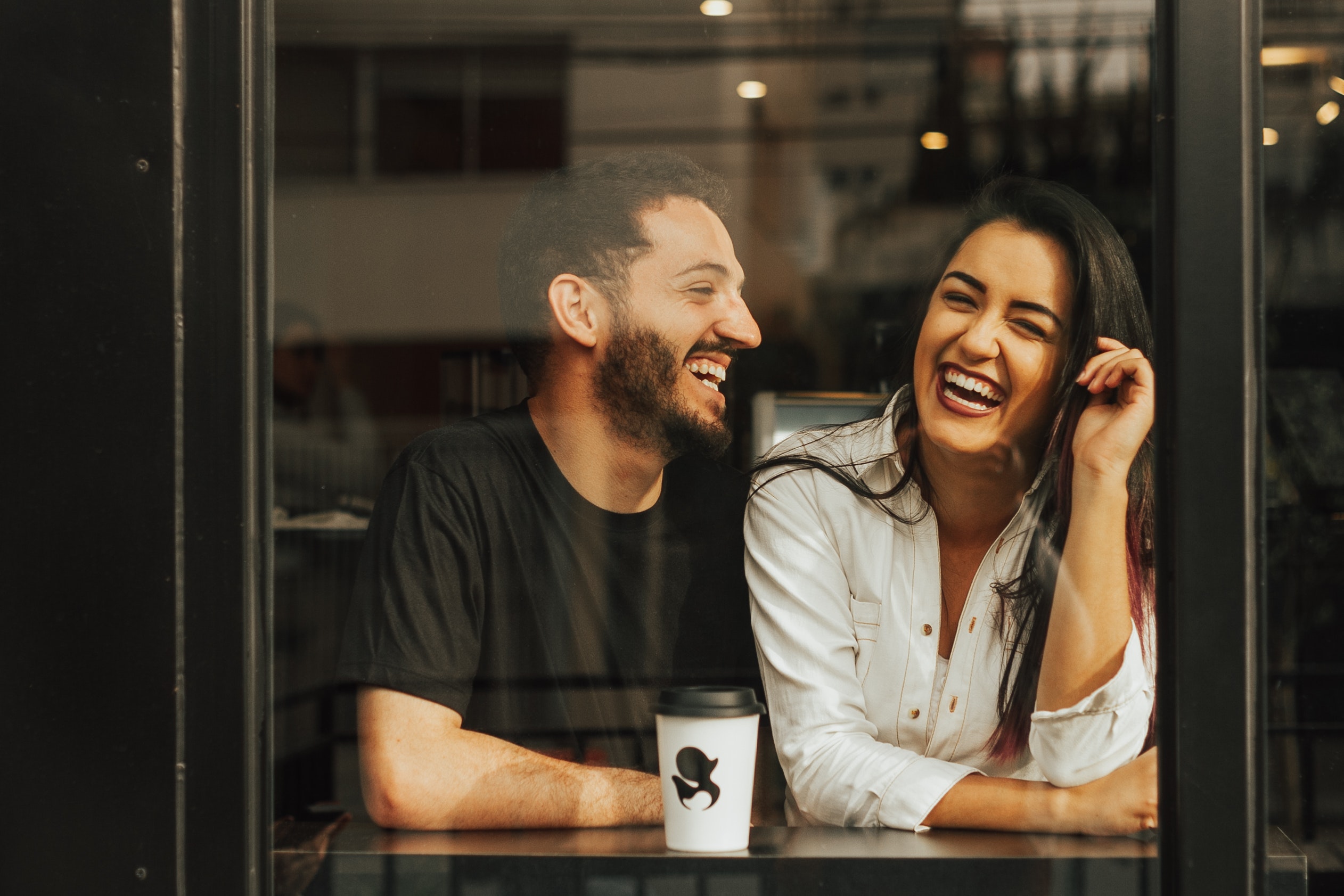 Photo of a laughing couple Sitting in a cafe. | Source: Pexels