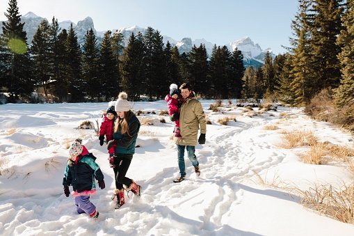 Family hiking below sunny, snowy mountains | Photo: Getty Images