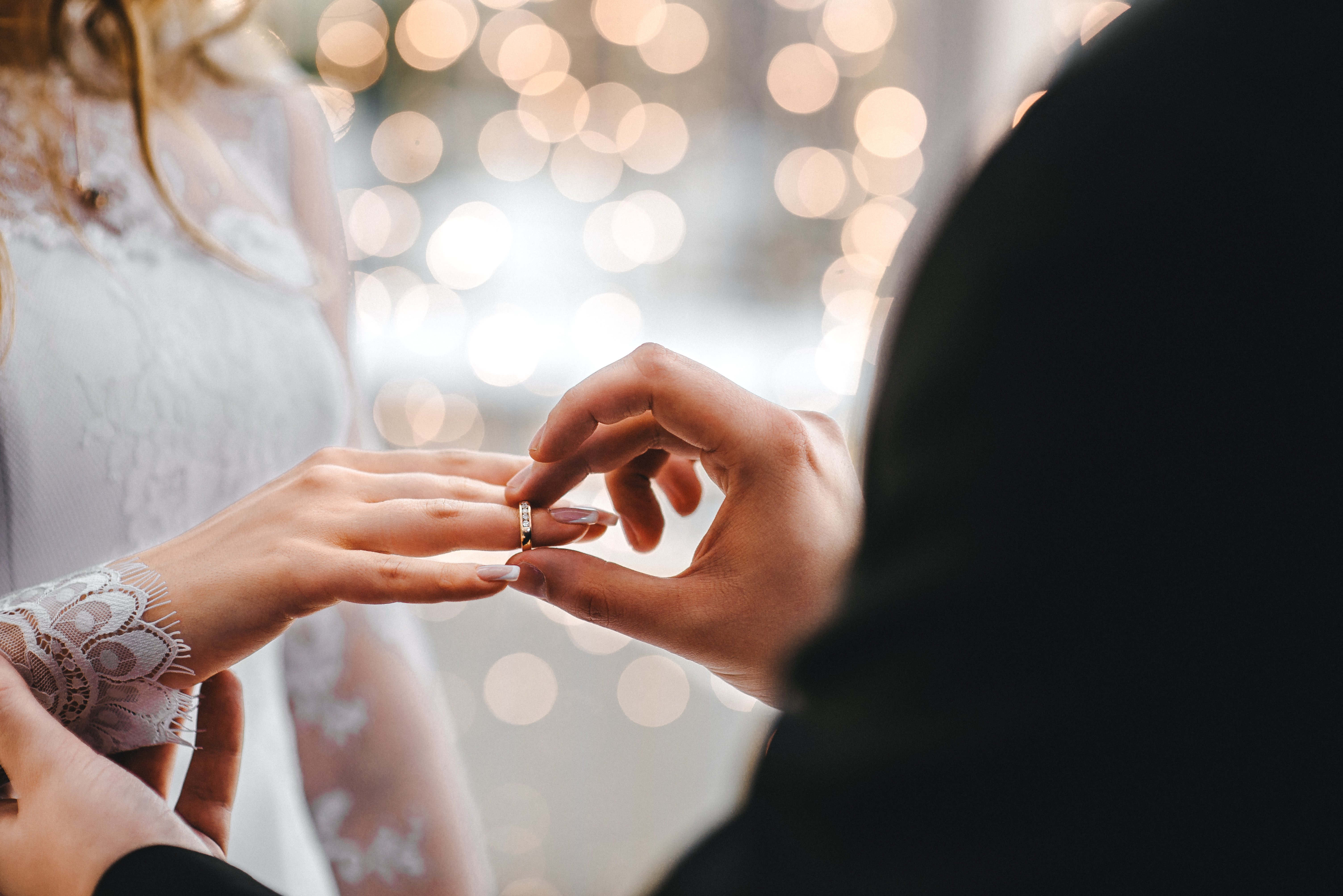Novio coloca anillo de bodas en la mano de novia. | Foto: Shutterstock