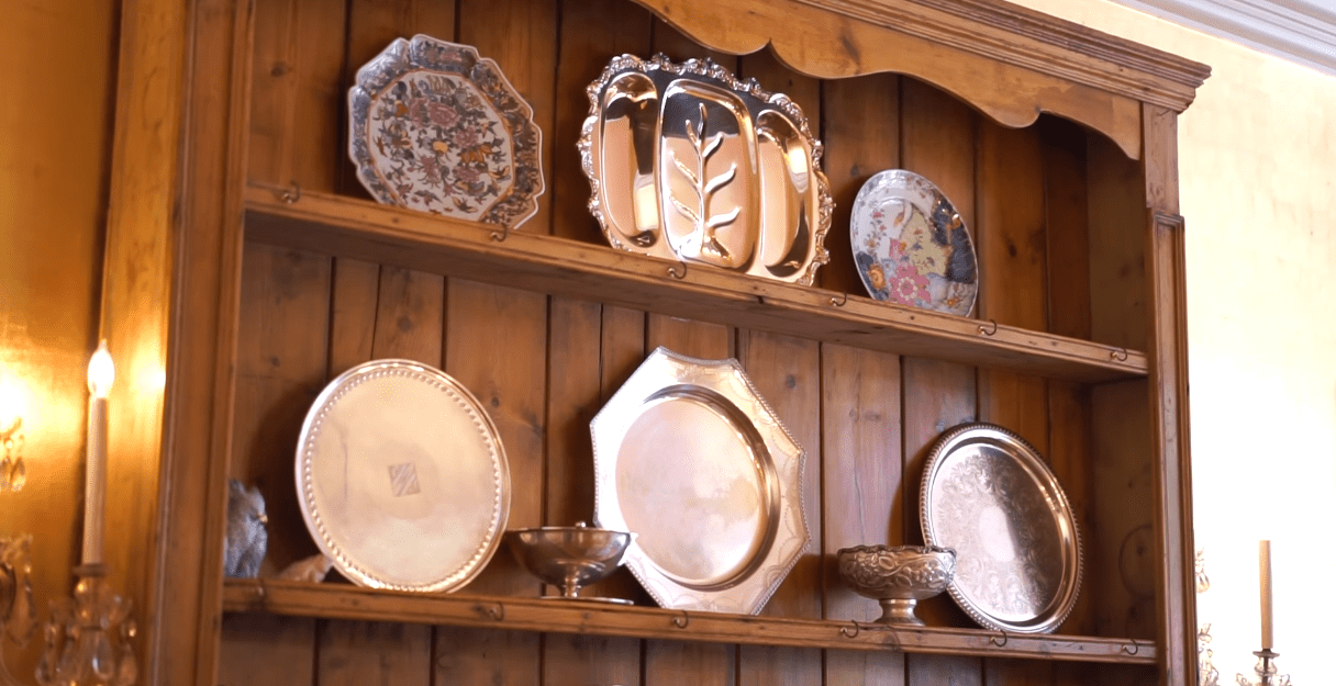 A  wooden cabinet in Donna Mills' dining room hosting her antique plates. / Source: YouTube/@LosAngelesTimes